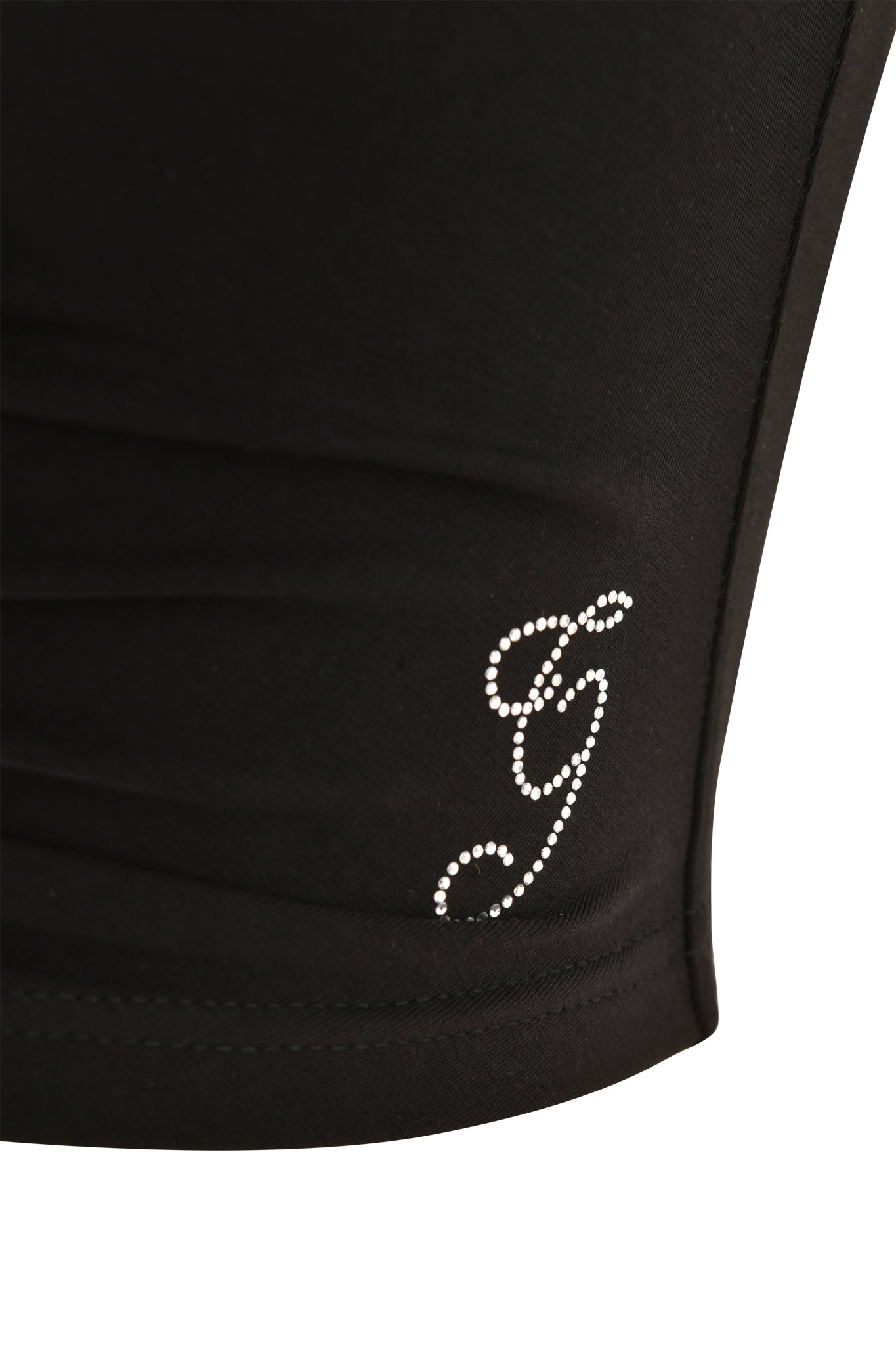 Close-up of the I.AM.GIA HALO TOP - SOLID BLACK, a soft halterneck crop top adorned with a rhinestone "G" near the seam.
