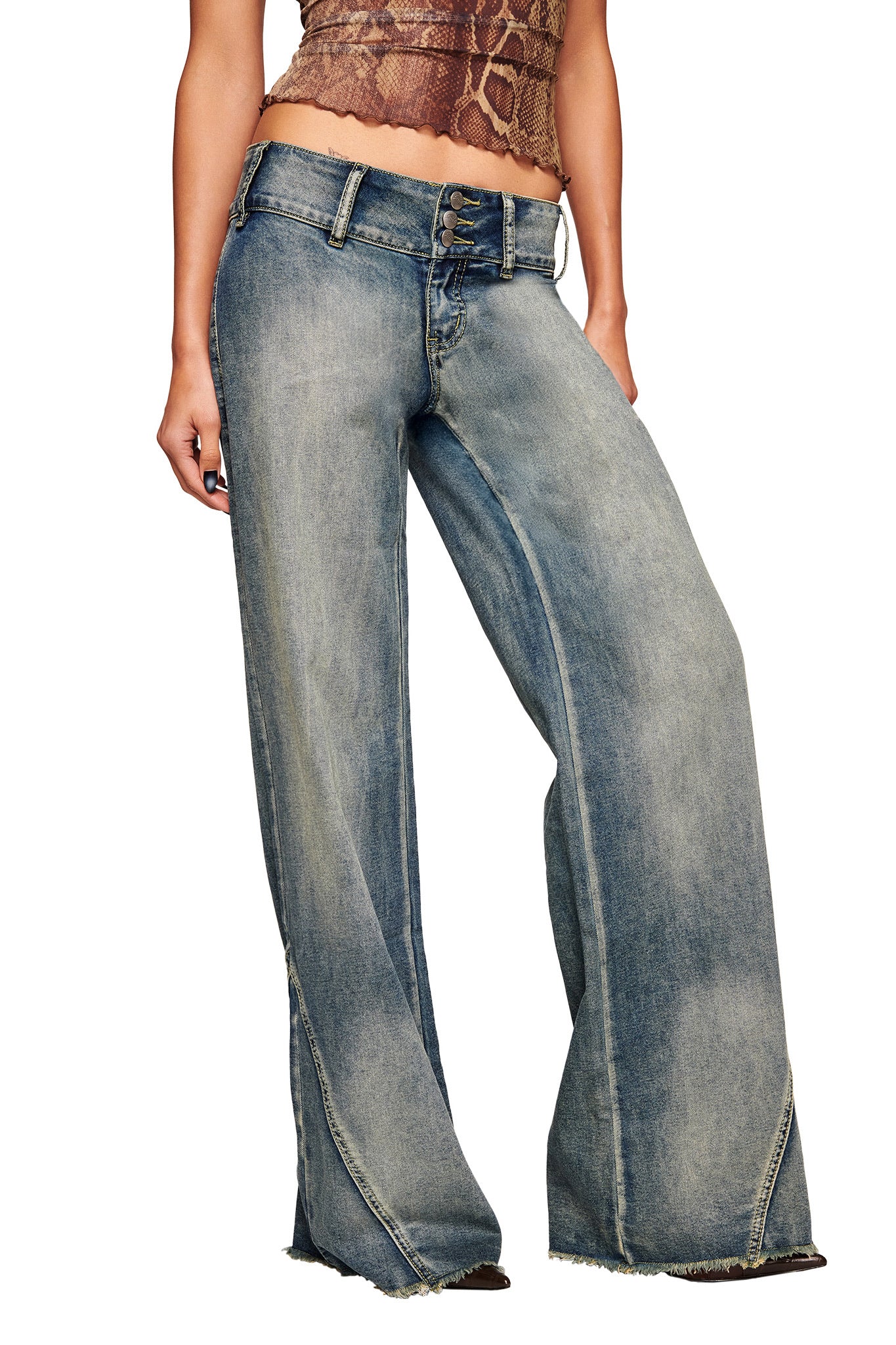 A person wearing I.AM.GIA's NYKKO JEAN - BLUE, featuring a high waist, wide waistband, faded wash, and frayed hems, paired with a brown snakeskin-patterned crop top. Only the lower torso, hips, and legs are visible.