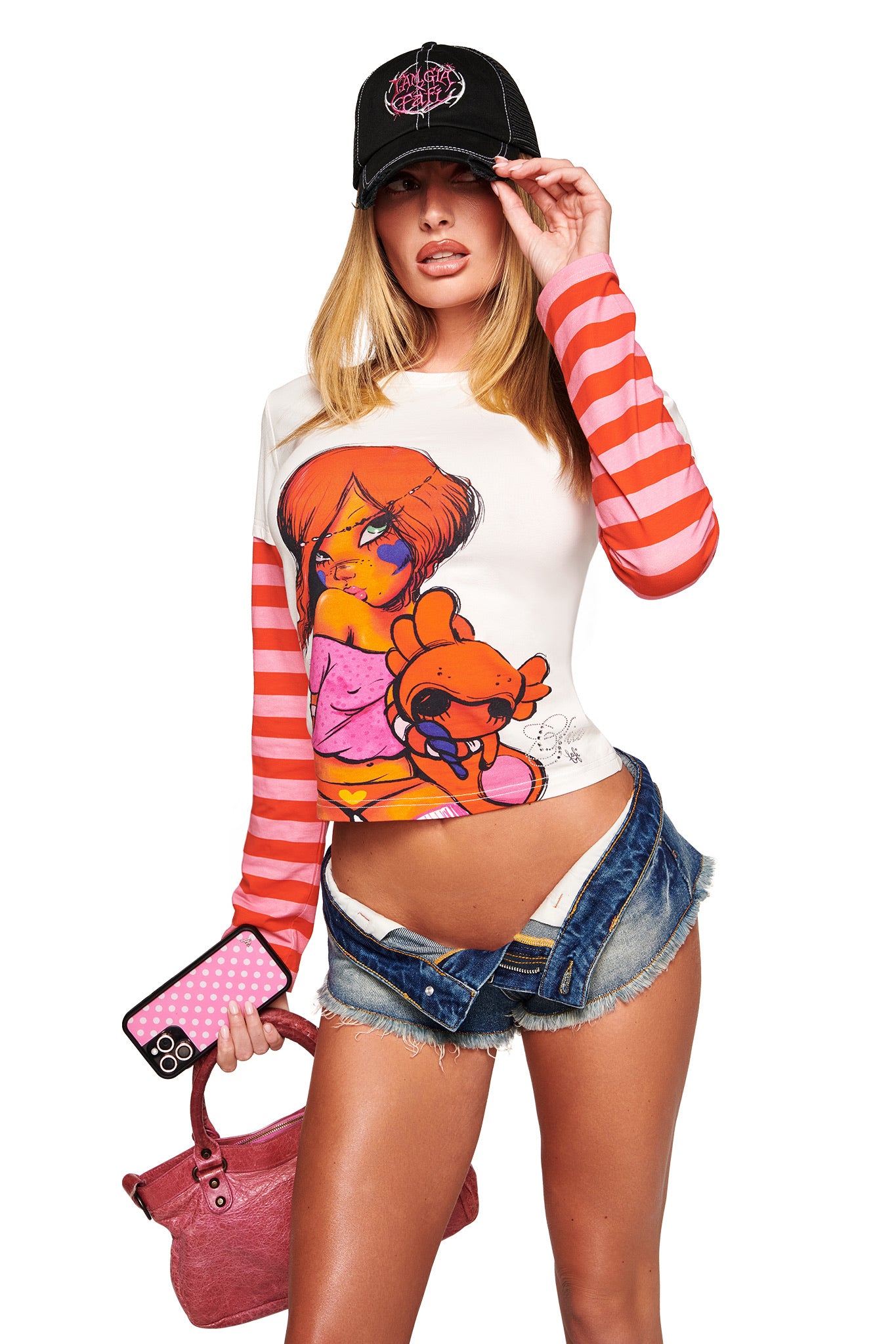 A woman poses in the I.AM.GIA FAFI DOUBLE LAYER TEE in white—a boxy, pink-striped top with a cartoon graphic—styled with denim shorts, a black cap, pink handbag, and phone for a playful fafinette collaboration vibe.