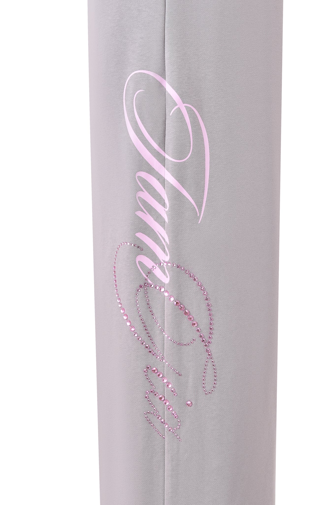 Close-up of light grey fabric from the KADE PANT - GREY by I.AM.GIA, featuring "Juicy" in pink script with pink rhinestones and printed accents.