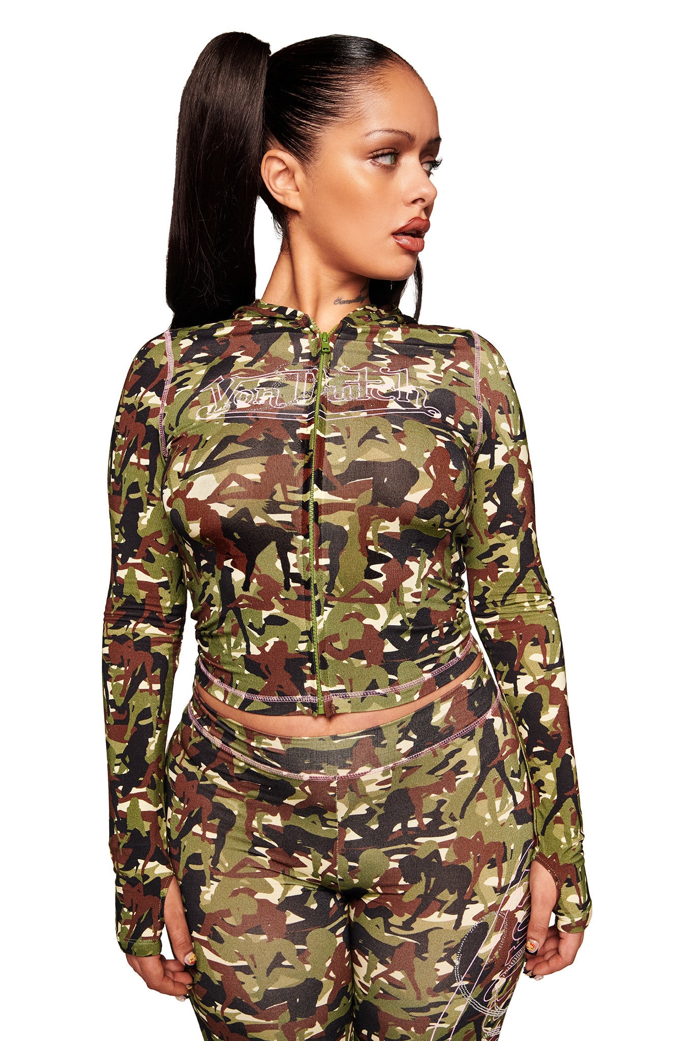 A woman with a sleek high ponytail wears the I.AM.GIA X VON DUTCH BLARE HOODIE in Gia Girl Camo, looking to the side against a white background.