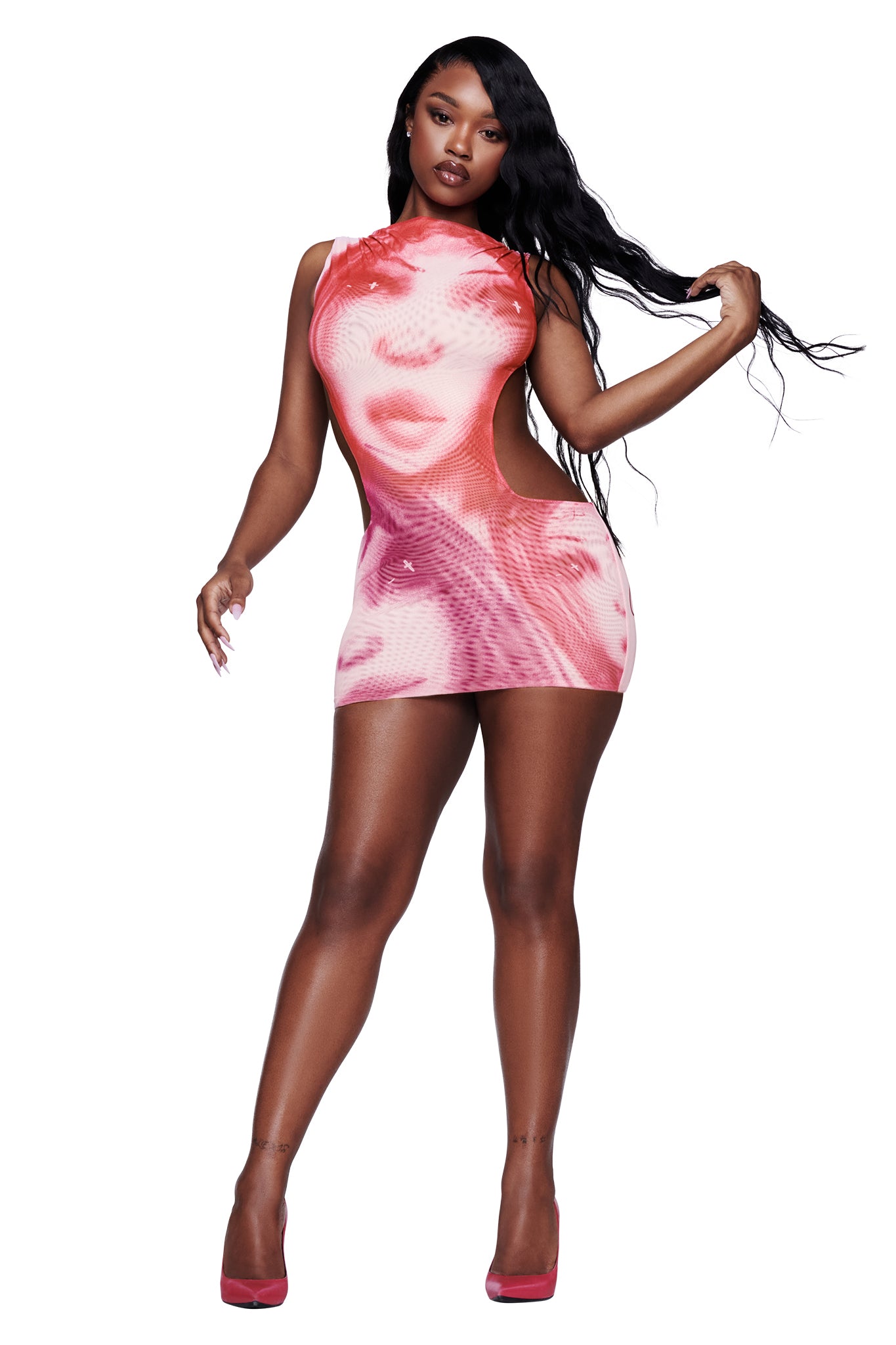 A woman poses in the I.AM.GIA T-REX CORALINE MINI DRESS in pink—a sleeveless micro mini dress featuring a striking large printed face design. With long black hair and pink heels, she stands against a white background, creating the perfect bold festival dress statement.