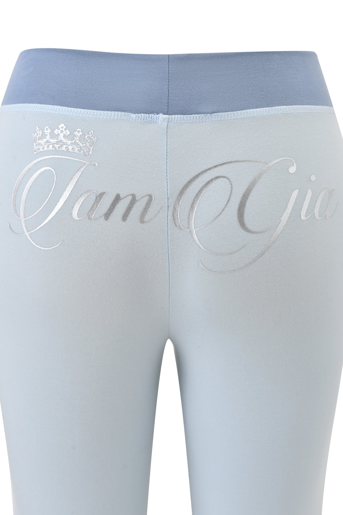 Close-up of the BLARE LOWER RISE TRACKPANT - TWO TONE POWDER BLUE by I.AM.GIA, featuring a powder blue body with a darker blue waistband and "I.AM.GIA" with a crown above the "I" printed in silver script on the upper back.