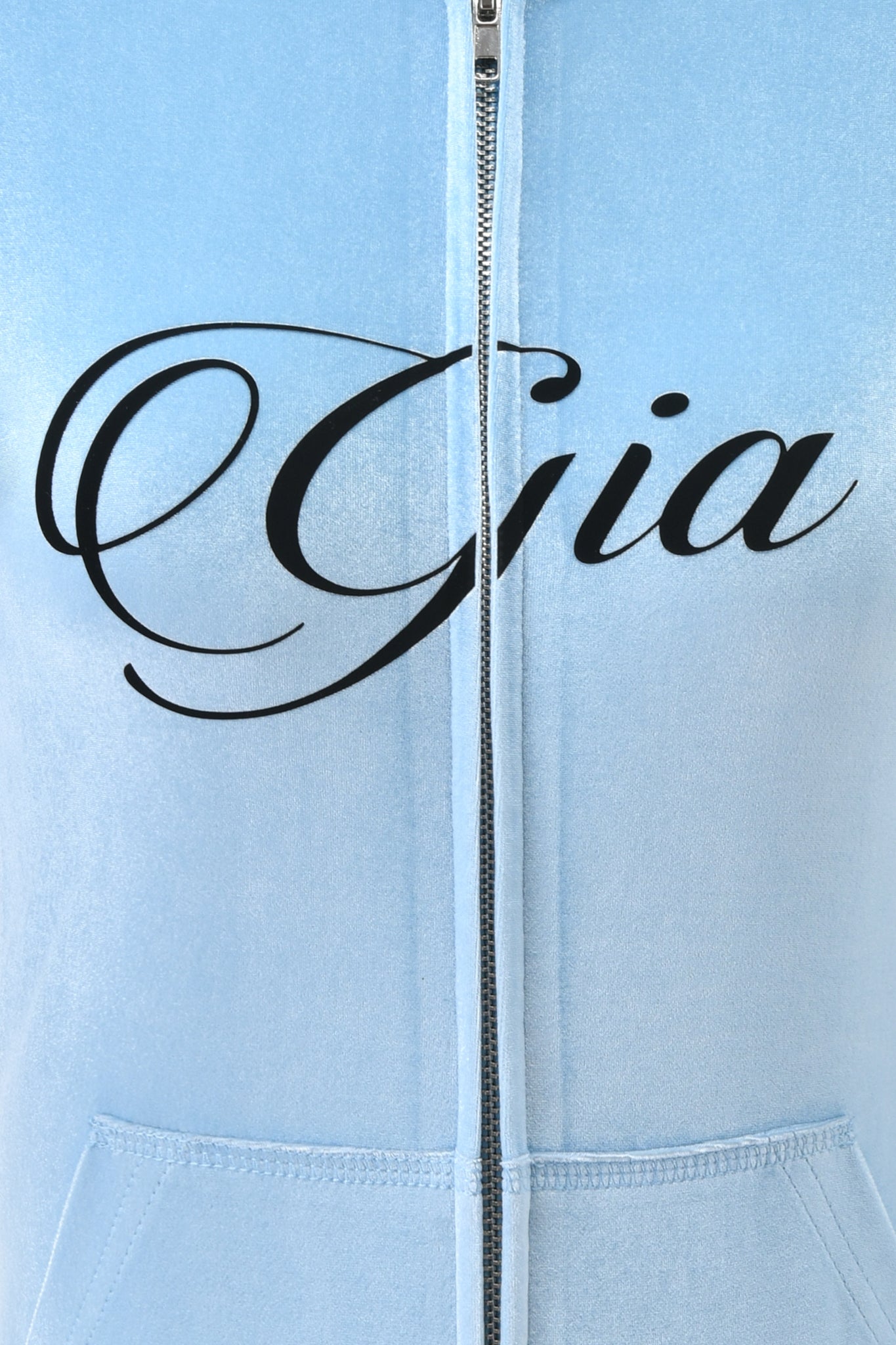 Close-up of the I.AM.GIA BLARE VELOUR POCKET HOODIE in Ice Blue, featuring "Gia" in bold black cursive on the chest, with a visible zipper and front pockets for added style.