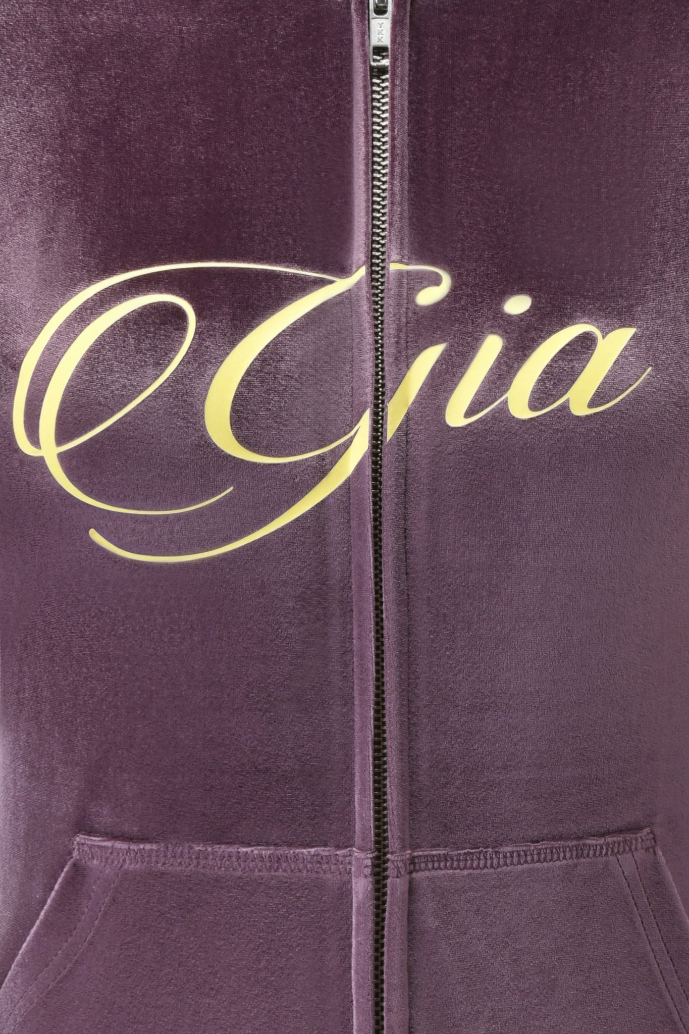 Close-up of the BLARE VELOUR POCKET HOODIE in purple by I.AM.GIA, featuring a zipper, bold yellow GIA script logo across the chest, and unique angel wing details.