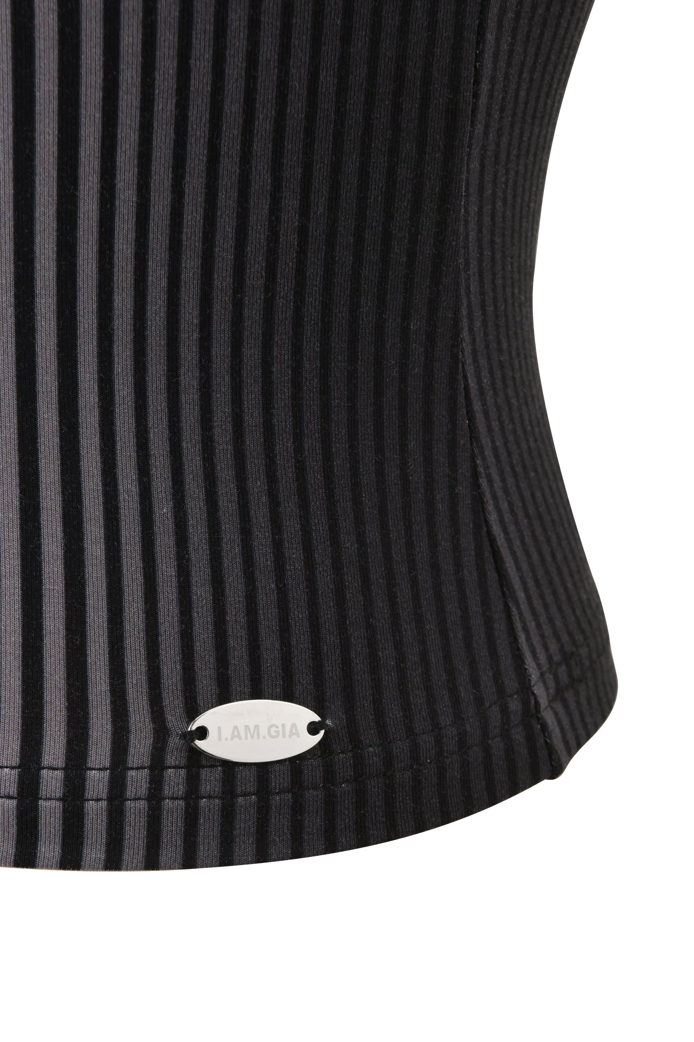 Close-up of the I.AM.GIA TRINITY BOOB TUBE - STRIPE, a black ribbed bamboo viscose jersey with vertical stripes and a small silver oval tag near the hem reading "I.AM.GIA.