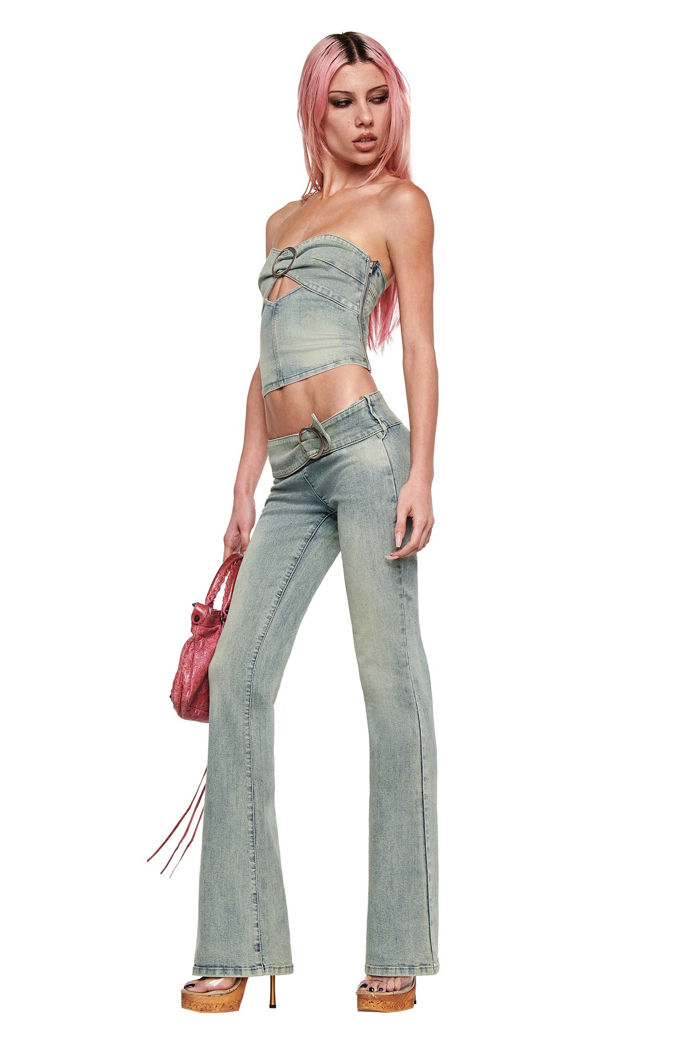 A person with long pink hair wears the I.AM.GIA JENN DENIM BOOB TUBE in blue, paired with flared denim pants, platform heels, and a pink handbag. The washed denim look stands out against a plain white background.