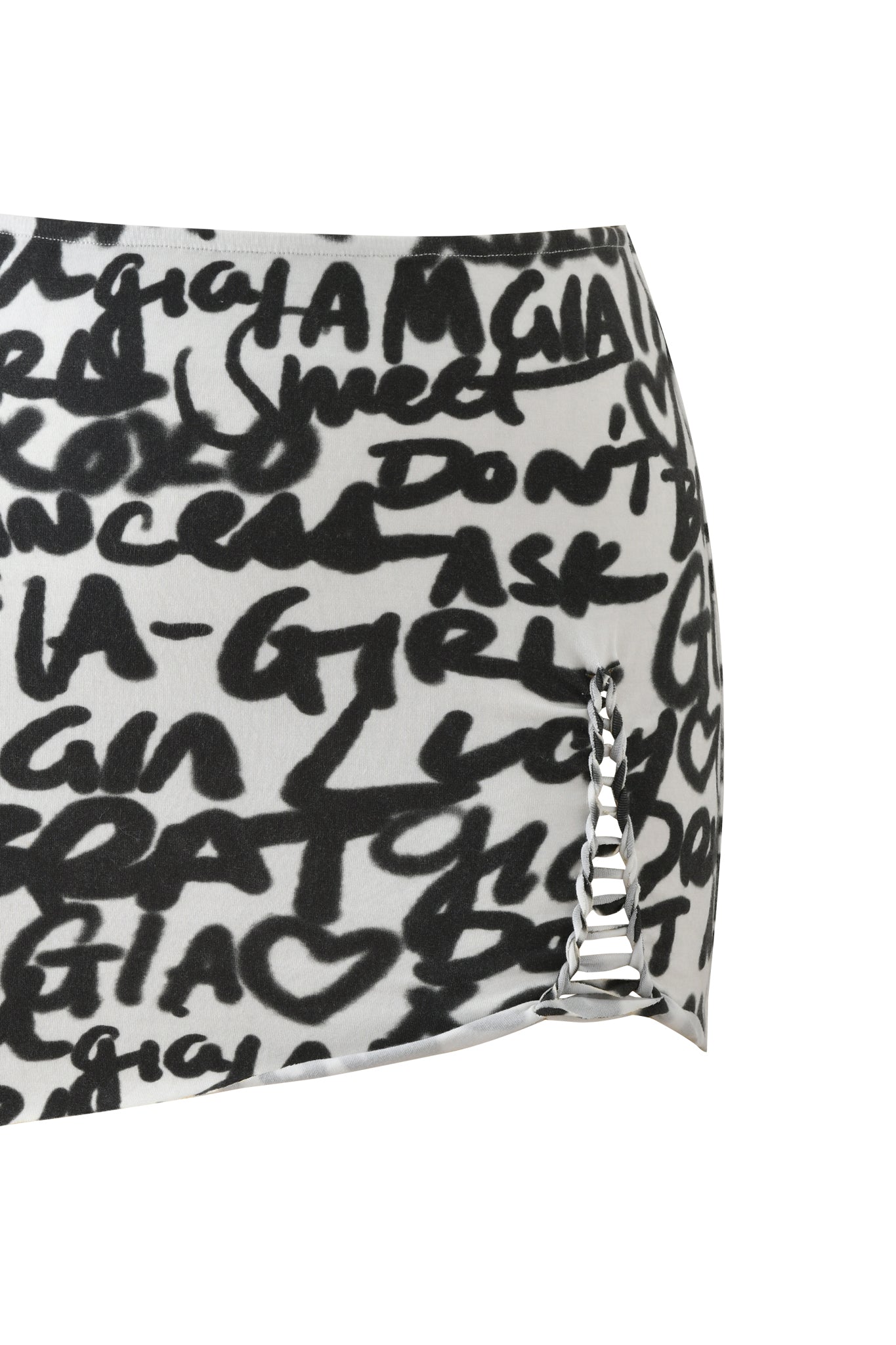 The HONEY MACRAME MINI SKIRT - WRITING ON THE WALL by I.AM.GIA is a white mini skirt featuring bold black graffiti-style text, heart motifs, and a subtle zigzag lace-up detail at the hem.