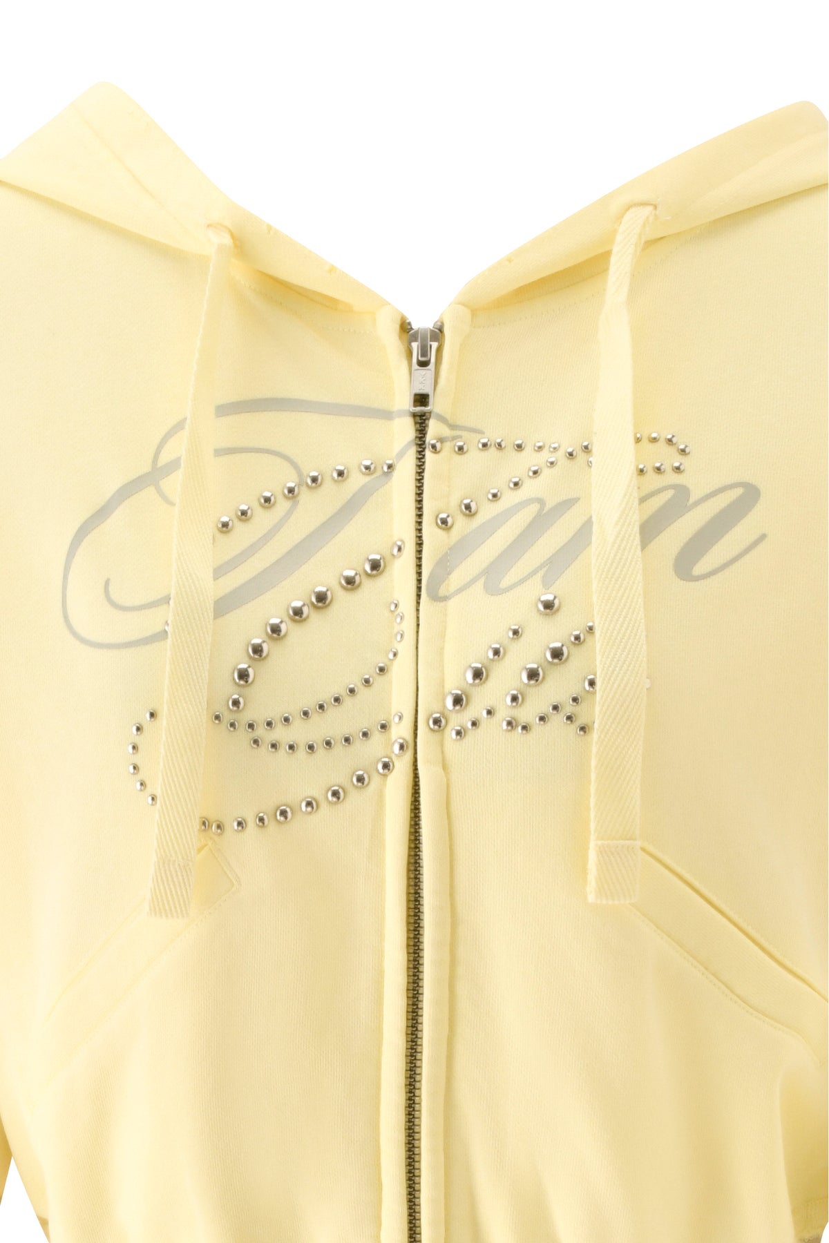 Close-up of a yellow hoodie with a zipper, adorned with silver studs spelling out “Damn” in cursive across the chest. Style it effortlessly with the I.AM.GIA VEDA PANT - YELLOW for an edgy, streetwear-inspired look.
