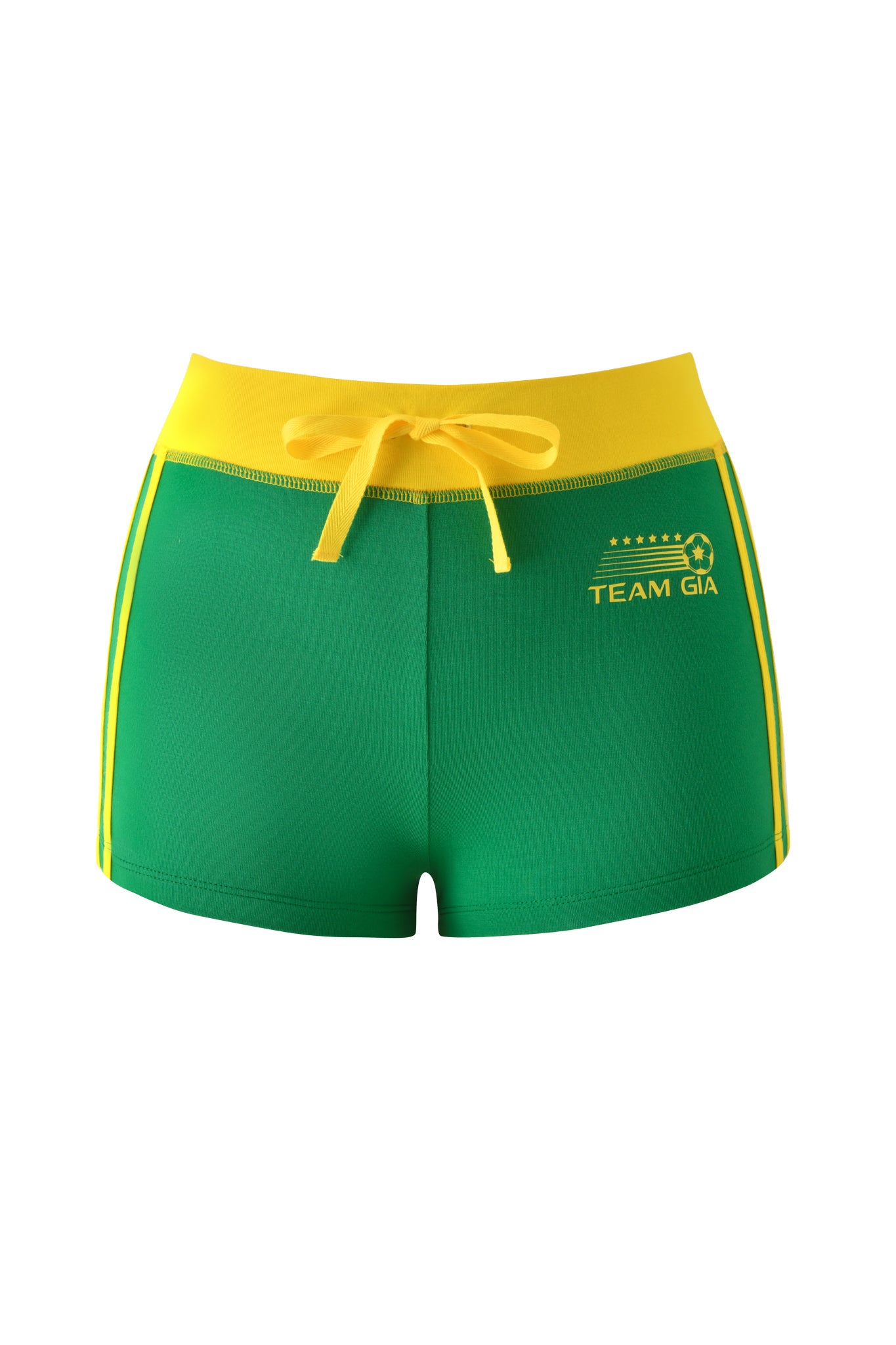 The I.AM.GIA BLARE PIPING SHORT - GREEN features a wide yellow waistband, yellow side stripes, and drawstring. Made from buttery-soft fabric, the left leg showcases a “TEAM GIA” logo with stars and a soccer ball.
