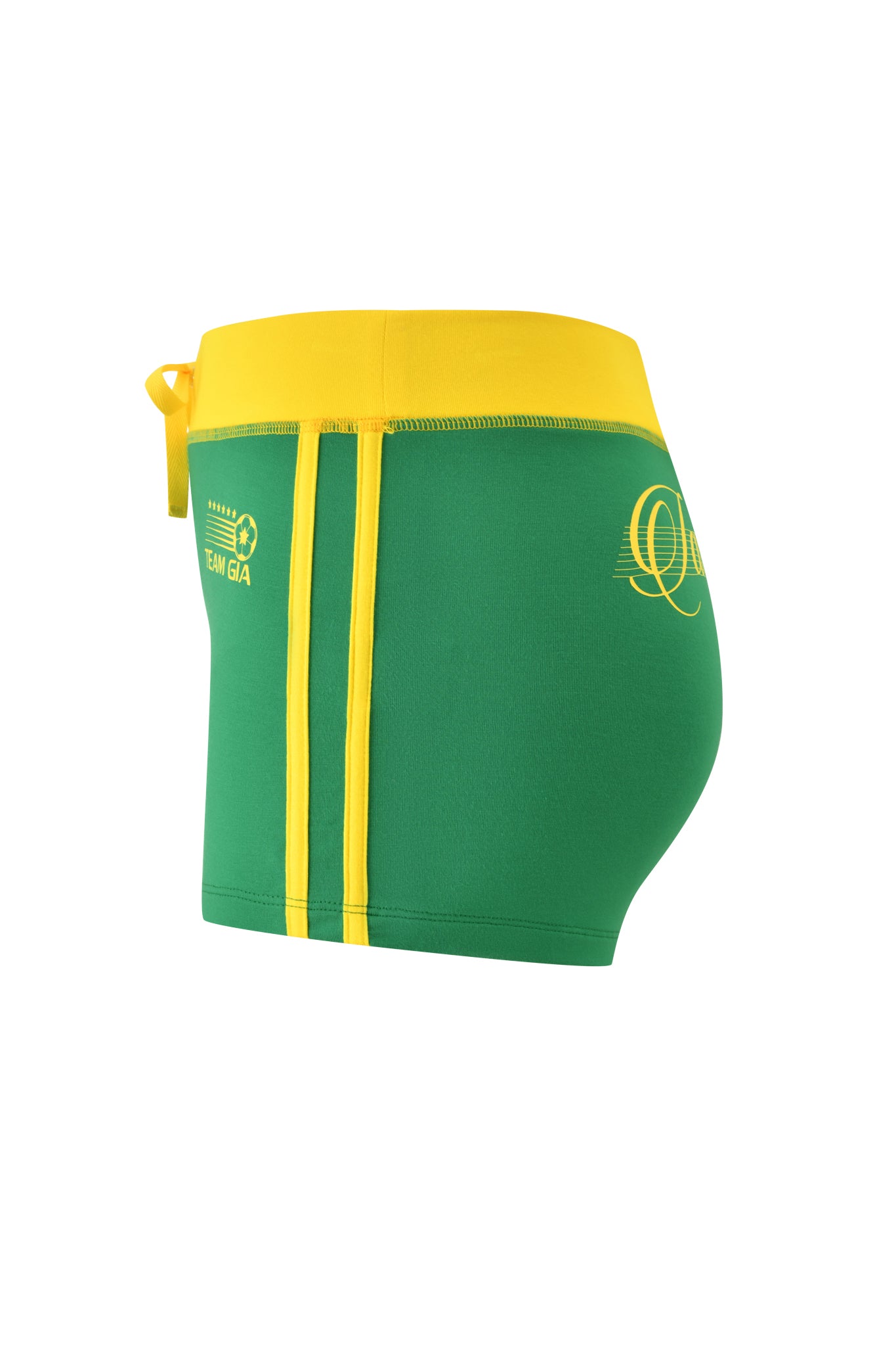 The BLARE PIPING SHORT - GREEN by I.AM.GIA features a green and yellow design with a yellow waistband, side tie, vertical stripes, "TEAM GA" logo on the left, and a decorative "Q" at the back in buttery-soft fabric.