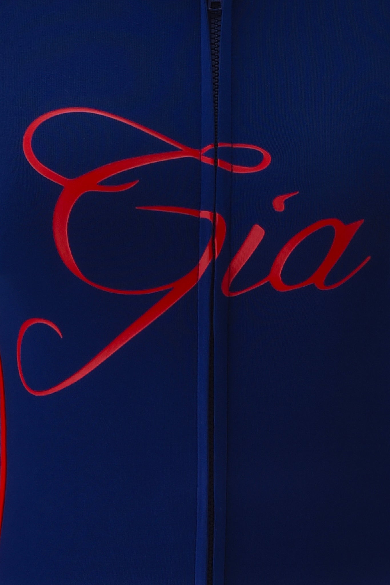 Close-up of the BLARE SPORT HOODIE AND HEADBAND - NAVY by I.AM.GIA, made from buttery-soft fabric. Features “Gia” in bold red script across the front and a visible center zipper for a sporty look.