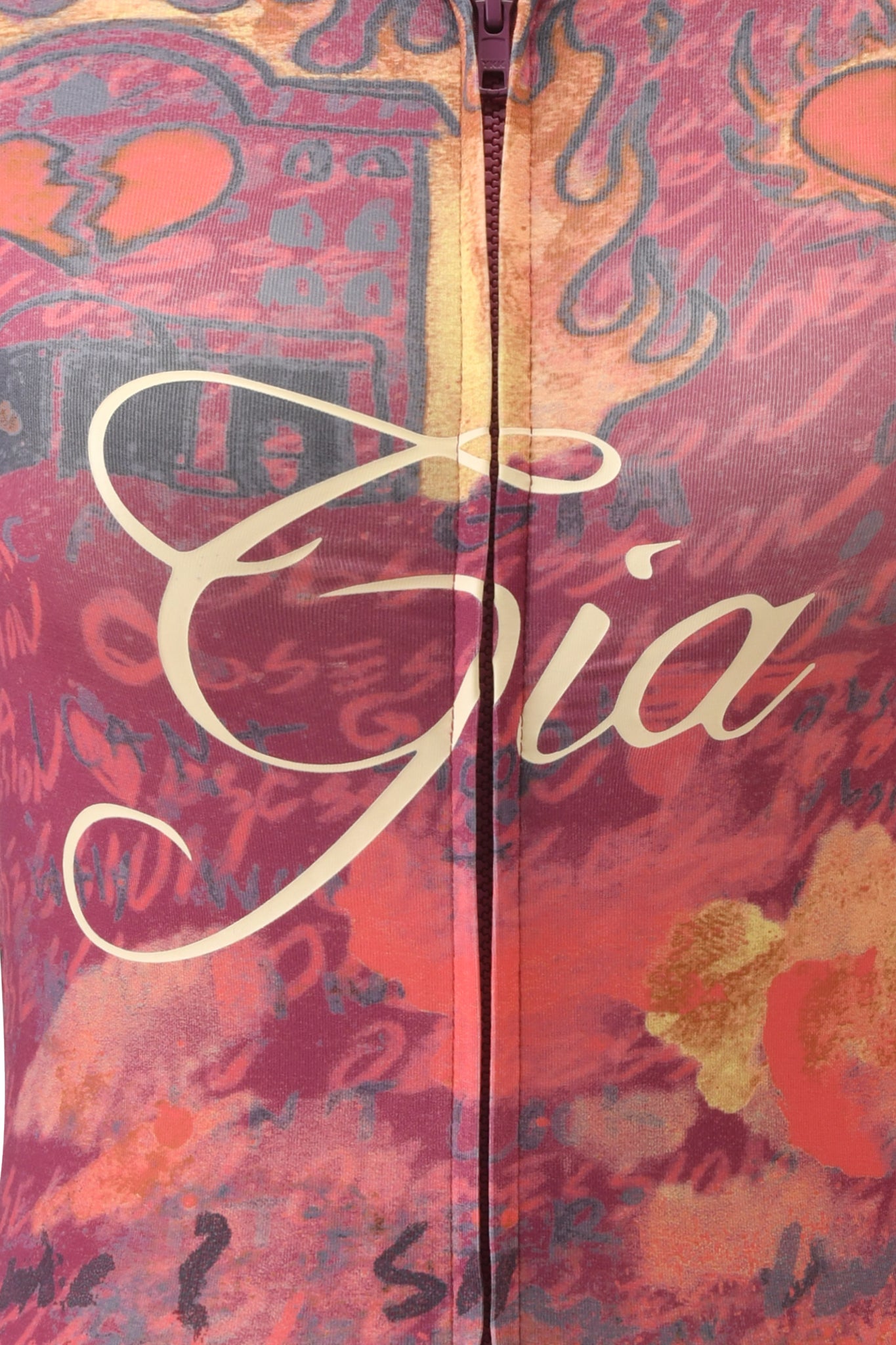 Close-up of a vibrant fabric featuring a zipper and the words "T-REX BLARE" in sleek script across the center, echoing the bold aesthetic of an I.AM.GIA hoodie. The background displays abstract patterns in shades of red, orange, and pink, reminiscent of the T-REX BLARE HOODIE by I.AM.GIA.