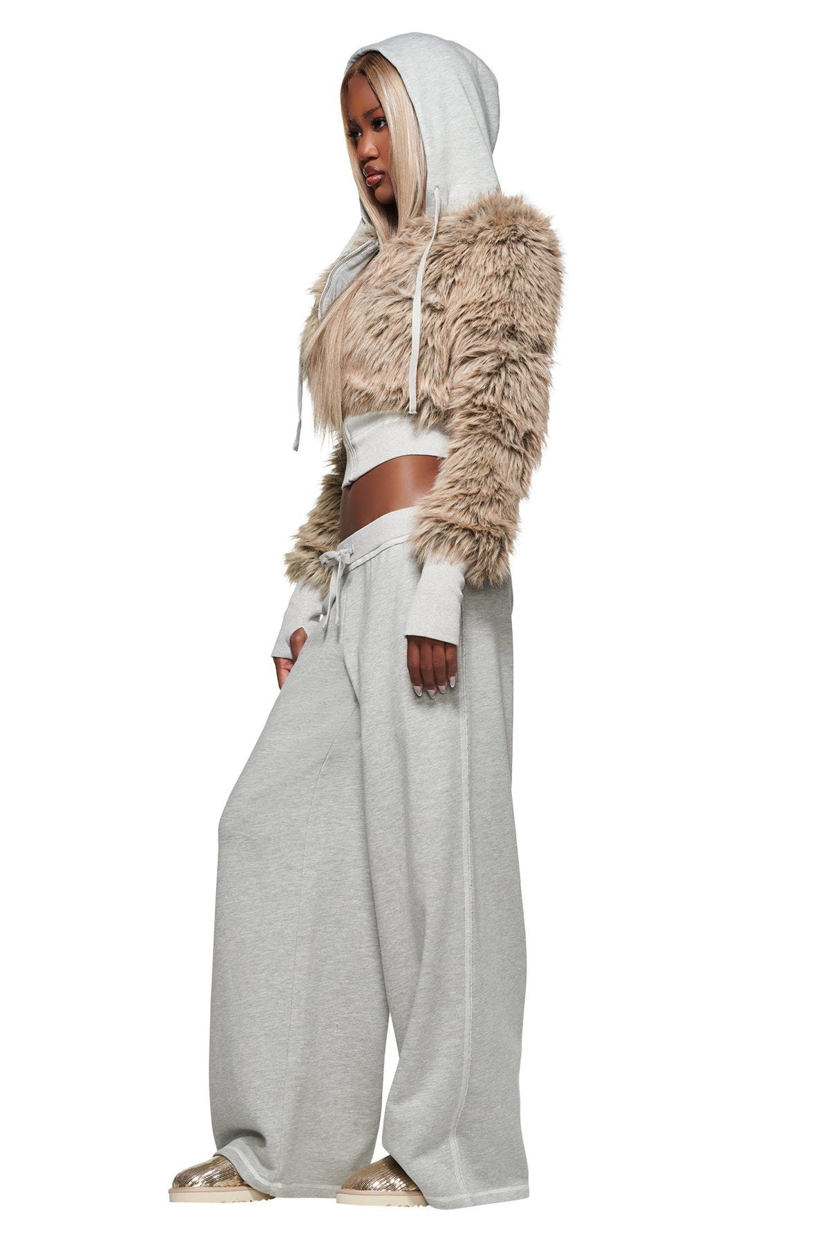 A person wearing the I.AM.GIA KOKO FUR FLEECE HOODIE in heather grey, paired with gray wide-leg sweatpants and sparkly flat shoes, stands facing sideways against a white background.