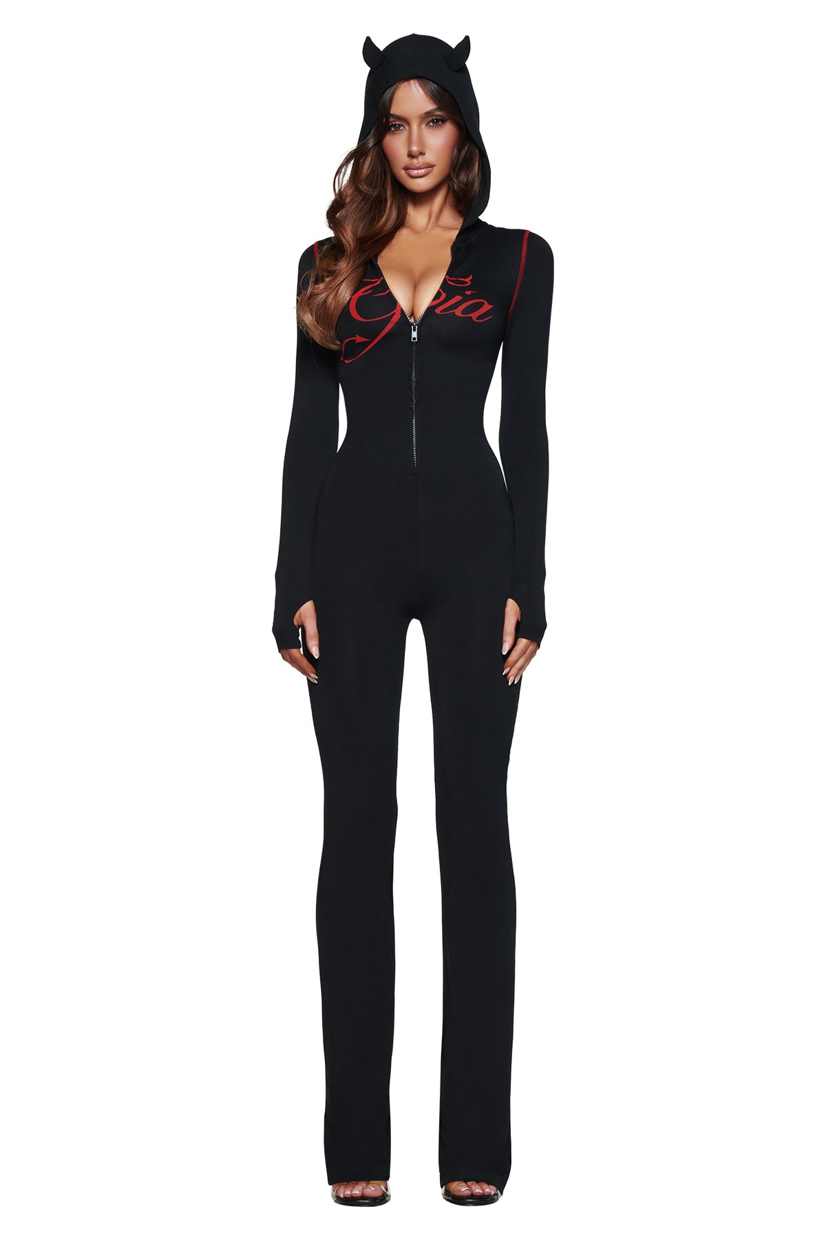 A woman wears the BLARE HORN JUMPSUIT - BLACK by I.AM.GIA, featuring red script, front zipper, long sleeves, and a devil horn hood, against a white background.