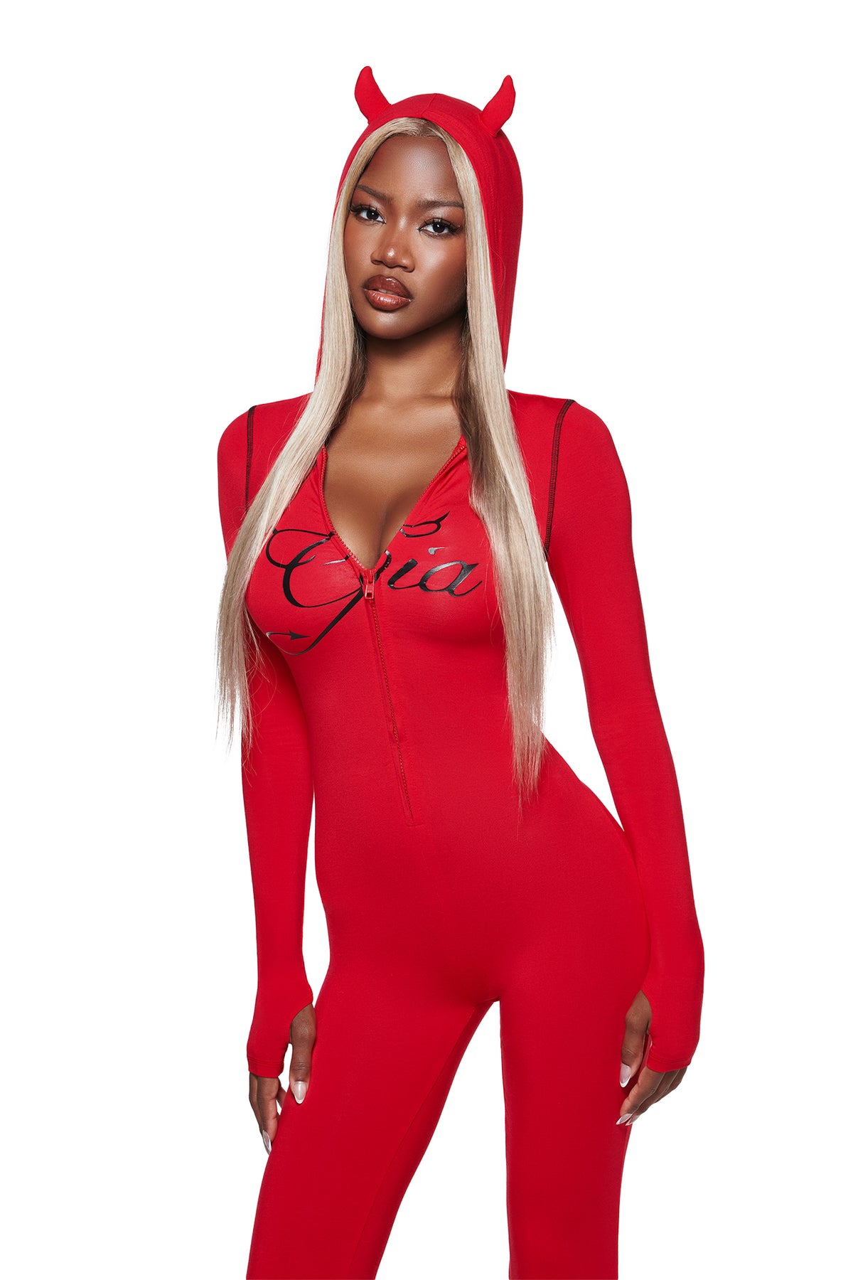 A woman in the I.AM.GIA BLARE HORN JUMPSUIT - RED with a devil horn hood stands facing forward, her long blonde hair straight and hands relaxed at her sides.