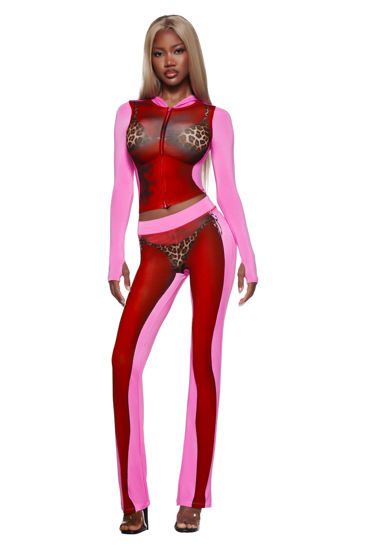 A woman wears the I.AM.GIA T-REX SPRAY BODY BLARE HOODIE - PINK, featuring sheer leopard print panels over a bikini body print, paired with open-toed heels and long straight blonde hair.