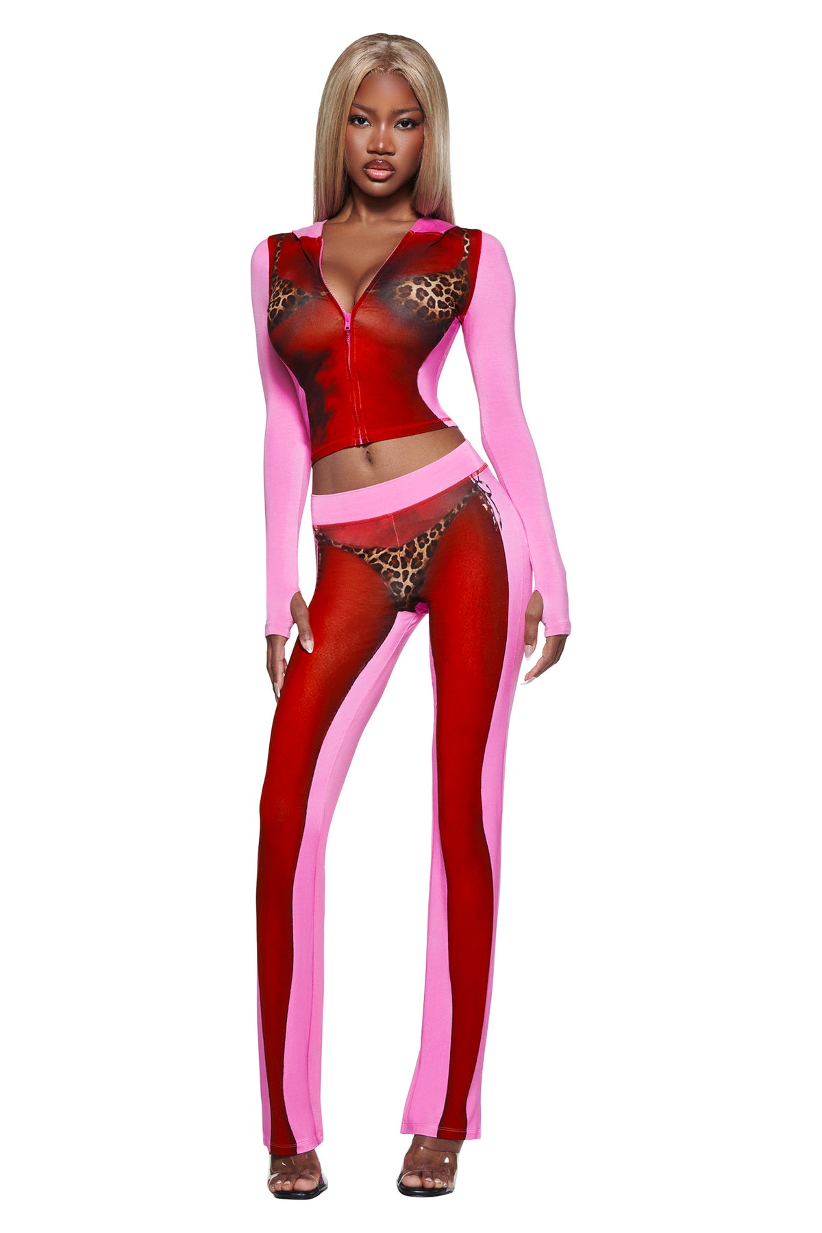 Woman sports a bold look in sheer red and pink panels with a zip-up crop top, leopard print bra and panties, styled with T-REX SPRAY BODY BLARE TRACKPANT - PINK by I.AM.GIA for chic airport vibes.