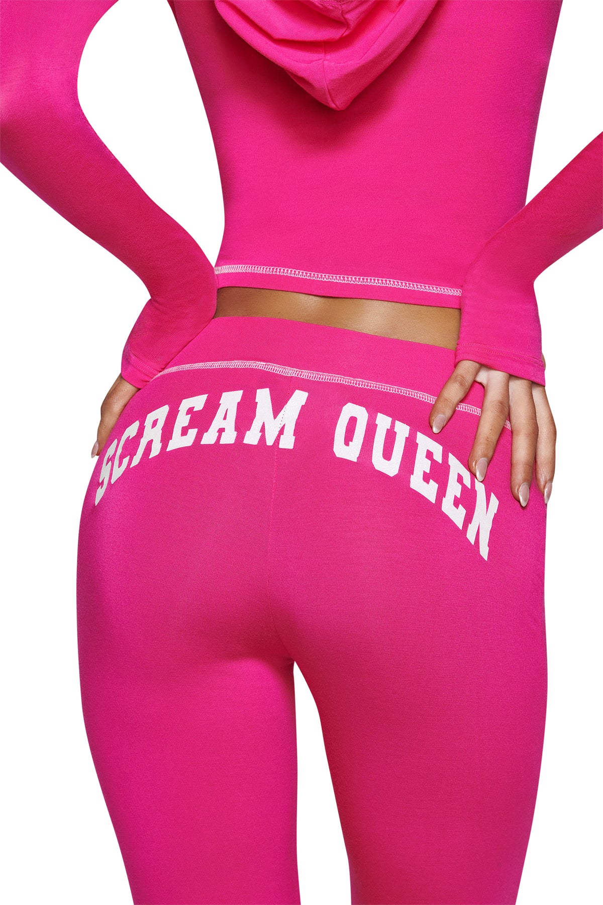 A person wearing the I.AM.GIA BLARE TRACKPANT - HOT PINK SCREAM QUEEN, featuring a fitted silhouette and bold ‘Scream Queen’ graphic in crisp white lettering across the lower back. The focus is on the hips and lower back.