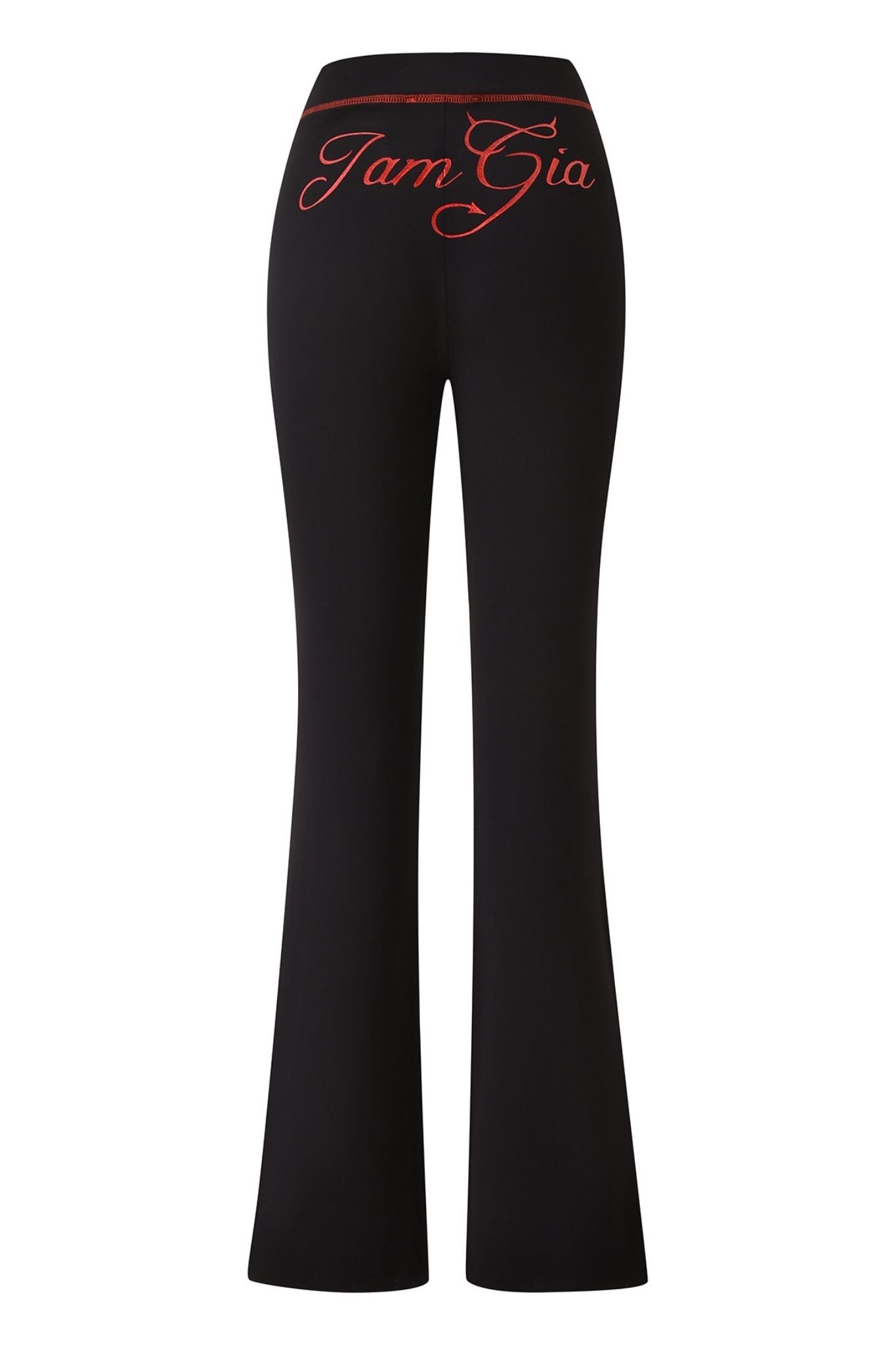 The BLARE TRACKPANT - JET BLACK : DEVIL by I.AM.GIA are black flared pants seen from the back, showcasing the bold devil GIA logo and “I am Gia” written in large red cursive letters across the waistband.