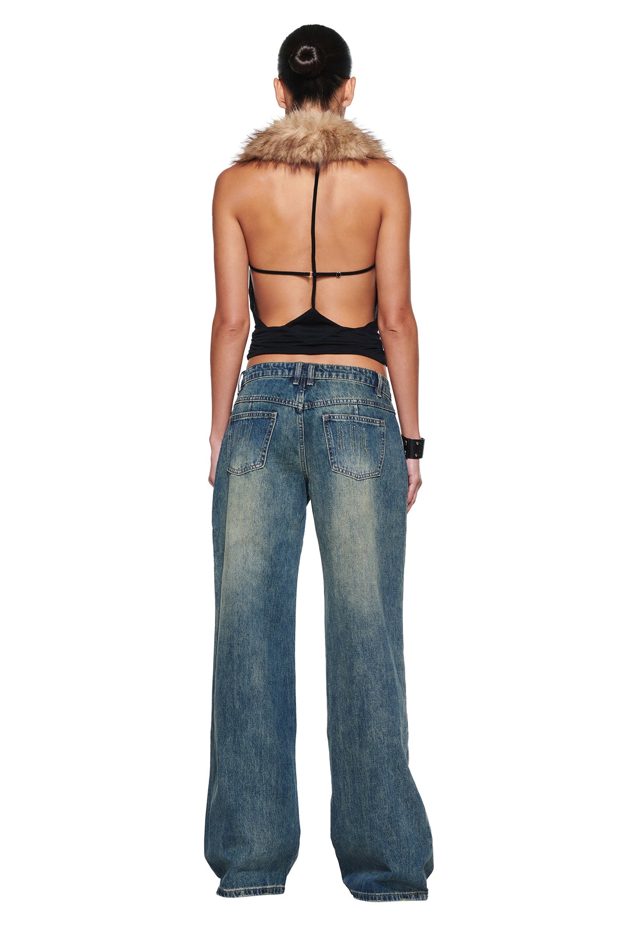 ANEESA COWL TOP - BLACK, a backless halter top with a faux fur collar and thin straps, worn with loose-fit blue jeans.
