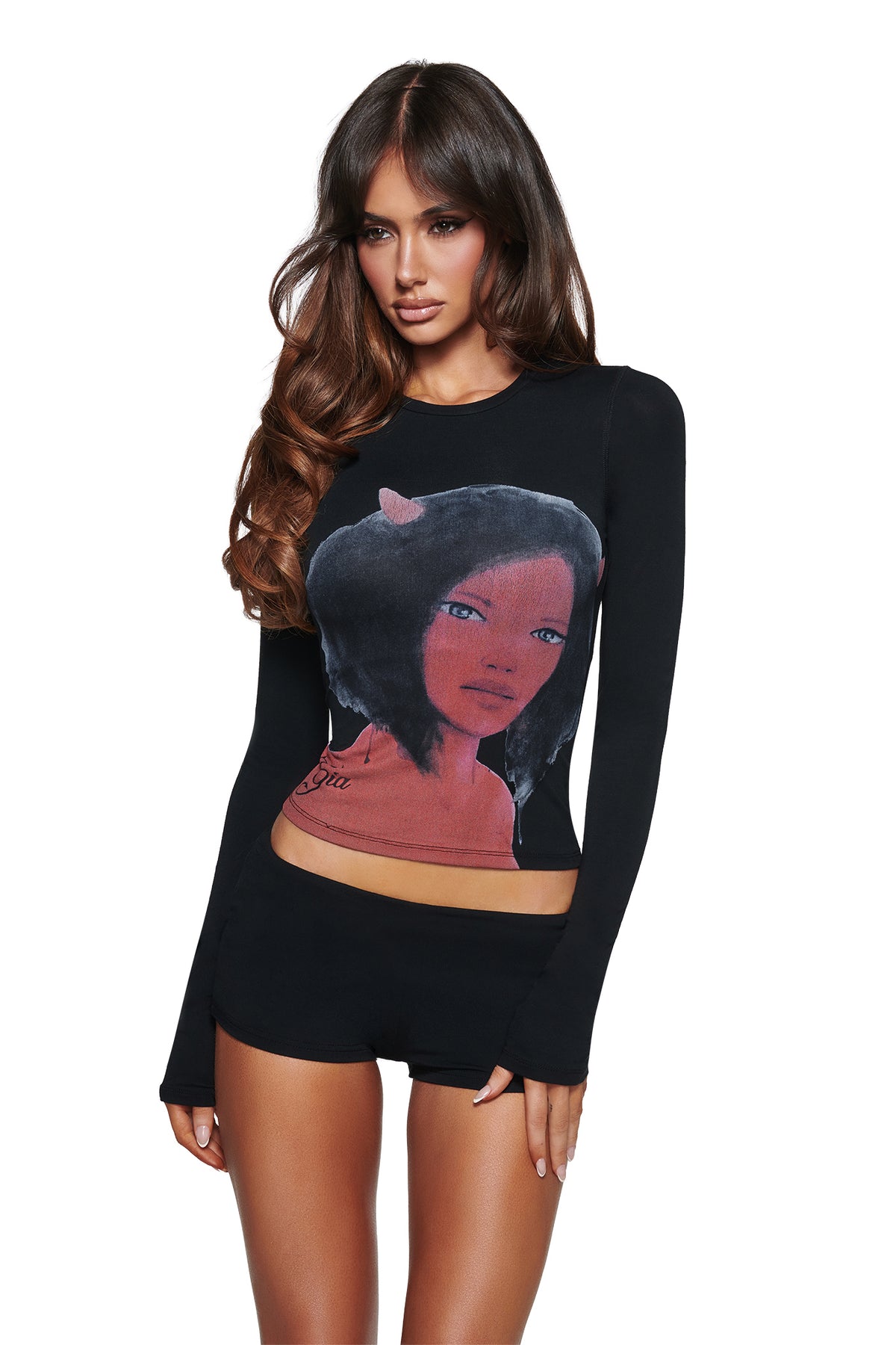 A woman with long brown hair wears the I.AM.GIA T-REX BLARE 2.0 LONG SLEEVE TEE - BLACK and matching shorts, featuring a bold graphic on a plain white background.