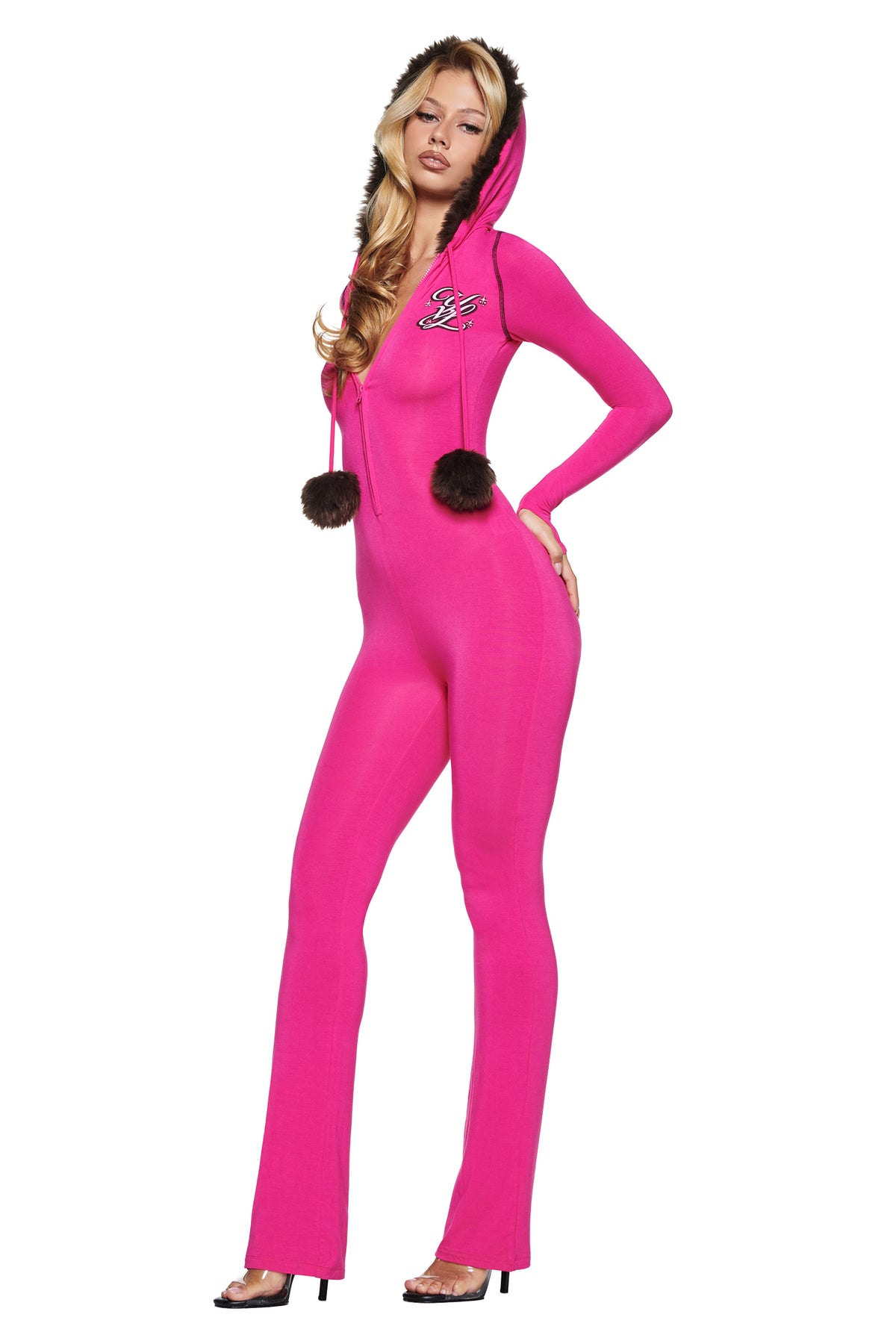 A person wearing a bright pink YVL BLARE FUR LINED JUMPSUIT with a faux fur hood and two fur pom-poms hanging from the neckline.