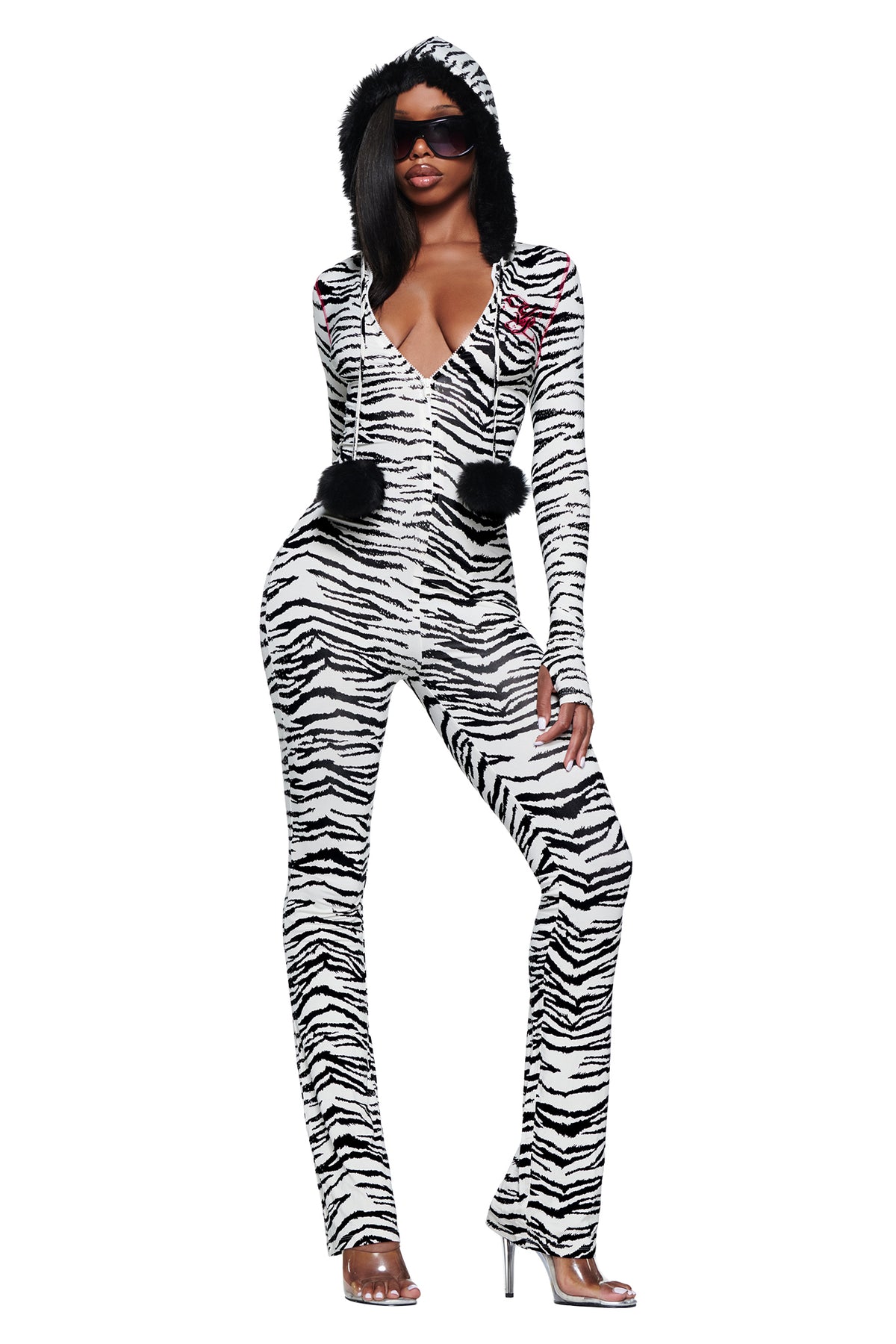 A person wears a long-sleeved zebra-print YVL BLARE FUR LINED JUMPSUIT - ZEBRA with a faux fur hood, featuring two black pom-poms hanging from the neckline.