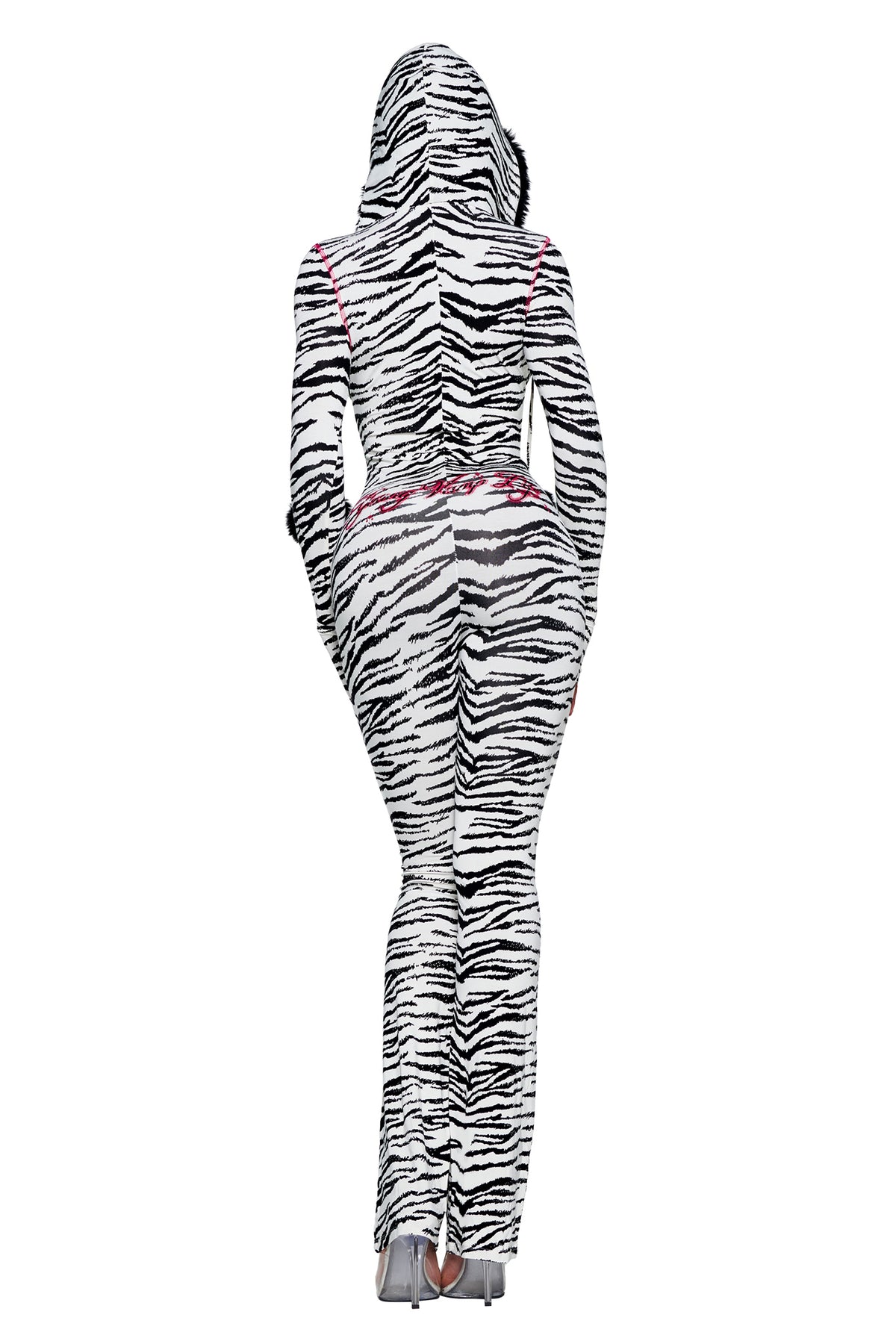 A person seen from the back wearing a YVL BLARE FUR LINED JUMPSUIT - ZEBRA, a long-sleeved, full-length zebra print jumpsuit with a hood and pink embroidered detailing at the waist.