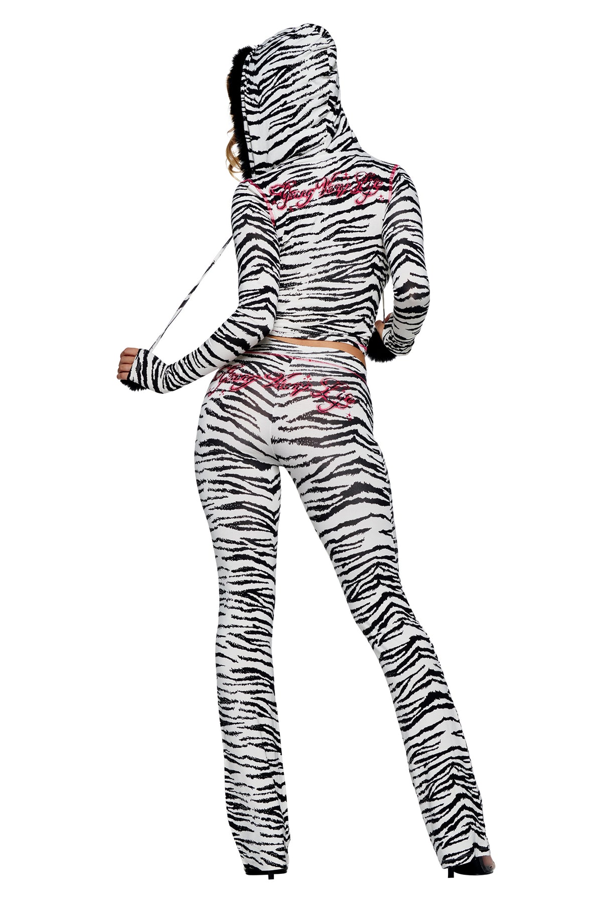 Back view of a person wearing a zebra-print hooded long-sleeve top and matching YVL BLARE TRACKPANT - ZEBRA with pink embroidered script.