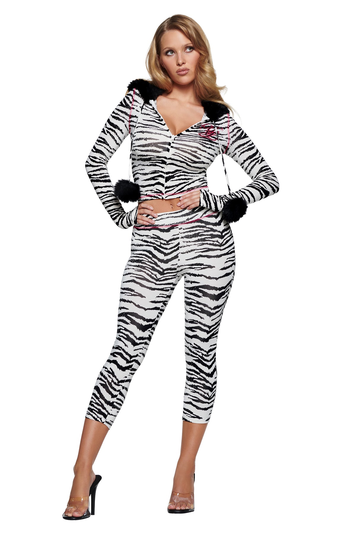 A woman wears a zebra print I.AM.GIA YVL BLARE CAPRI - ZEBRA pant and matching long-sleeved, zip-up cropped hoodie, both featuring black fur trim on the hood and sleeve cuffs.