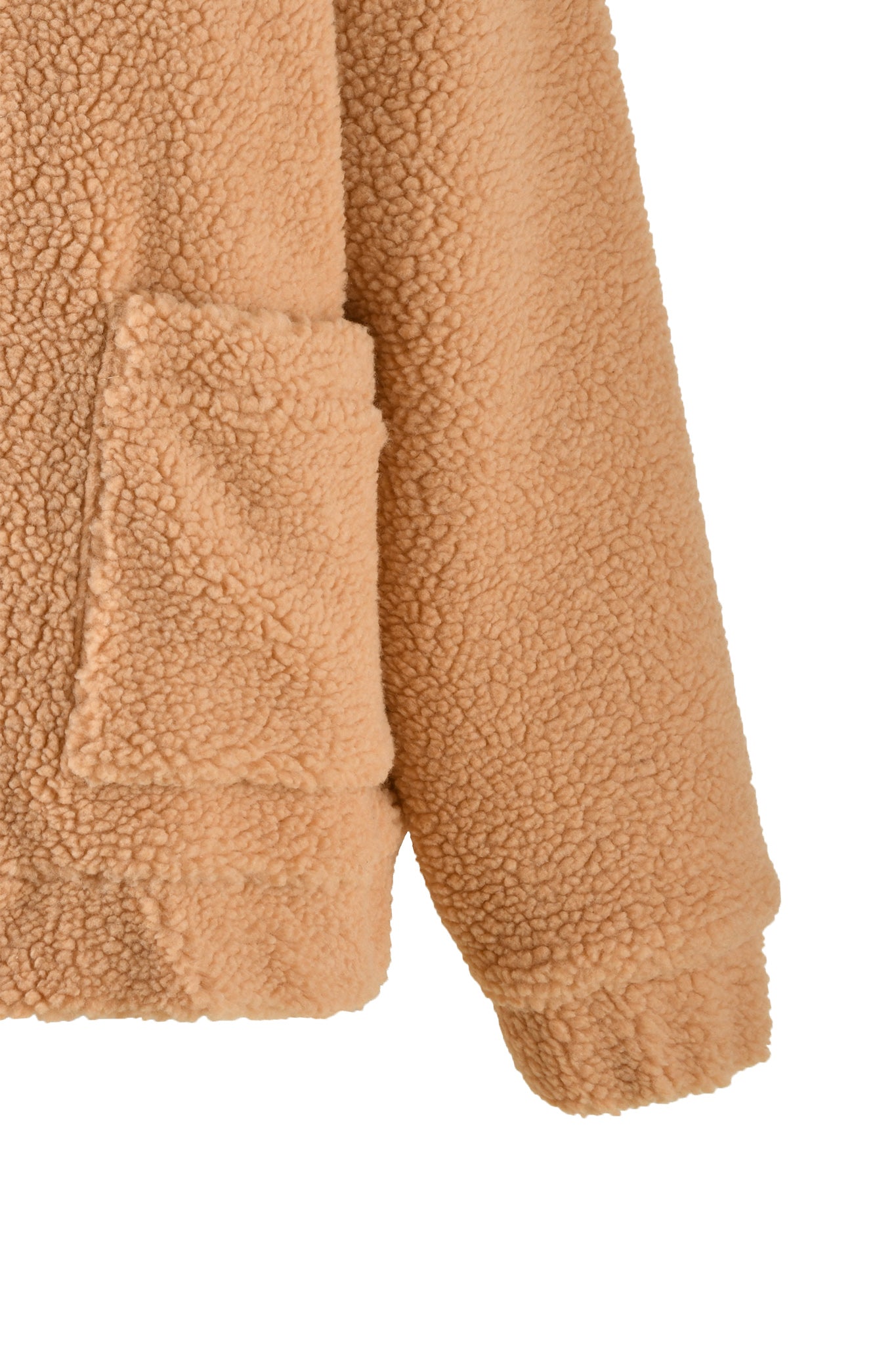 A close-up view of the PIXIE COAT - CARAMEL by I.AM.GIA, showcasing the lower part of a sleeve and a pocket. The tan-colored fabric has a fluffy, sherpa-like appearance, with a small portion of the hem visible at the bottom.