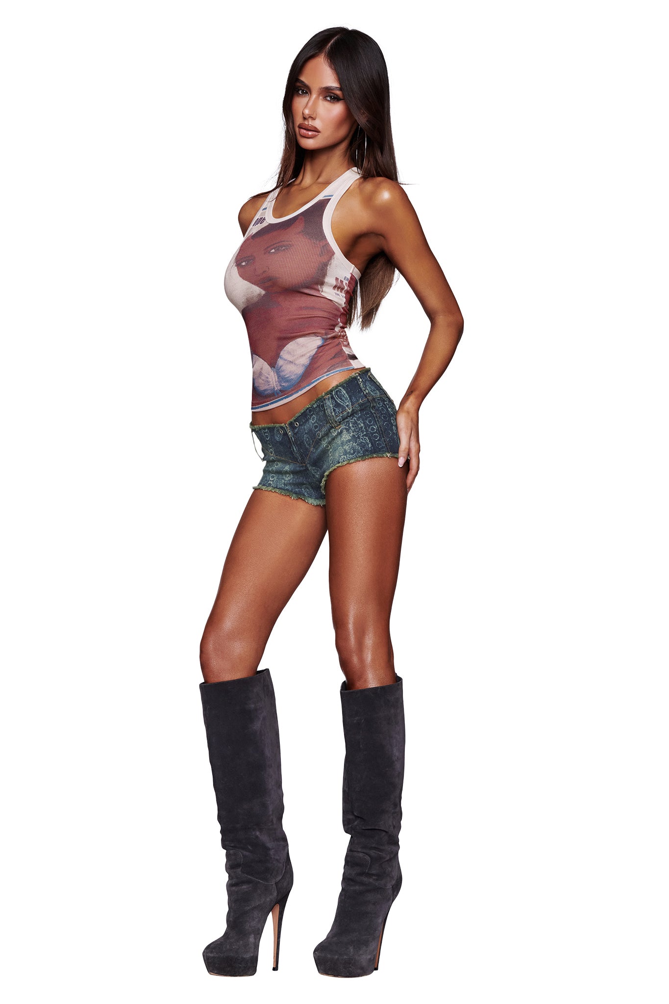 A woman with long brown hair wears the I.AM.GIA T-REX PENELOPE TANK in white, paired with short denim shorts and knee-high gray heeled boots, posing with one hand on her hip against a white background.
