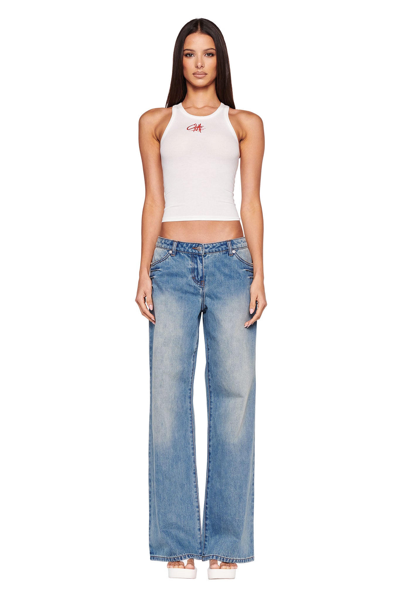 A woman with long, straight hair is wearing a white, sleeveless crop top and high-waisted DYLAN JEAN - BLUE : LIGHT BLUE from I.AM.GIA. She is standing and looking directly at the camera against a plain white background.