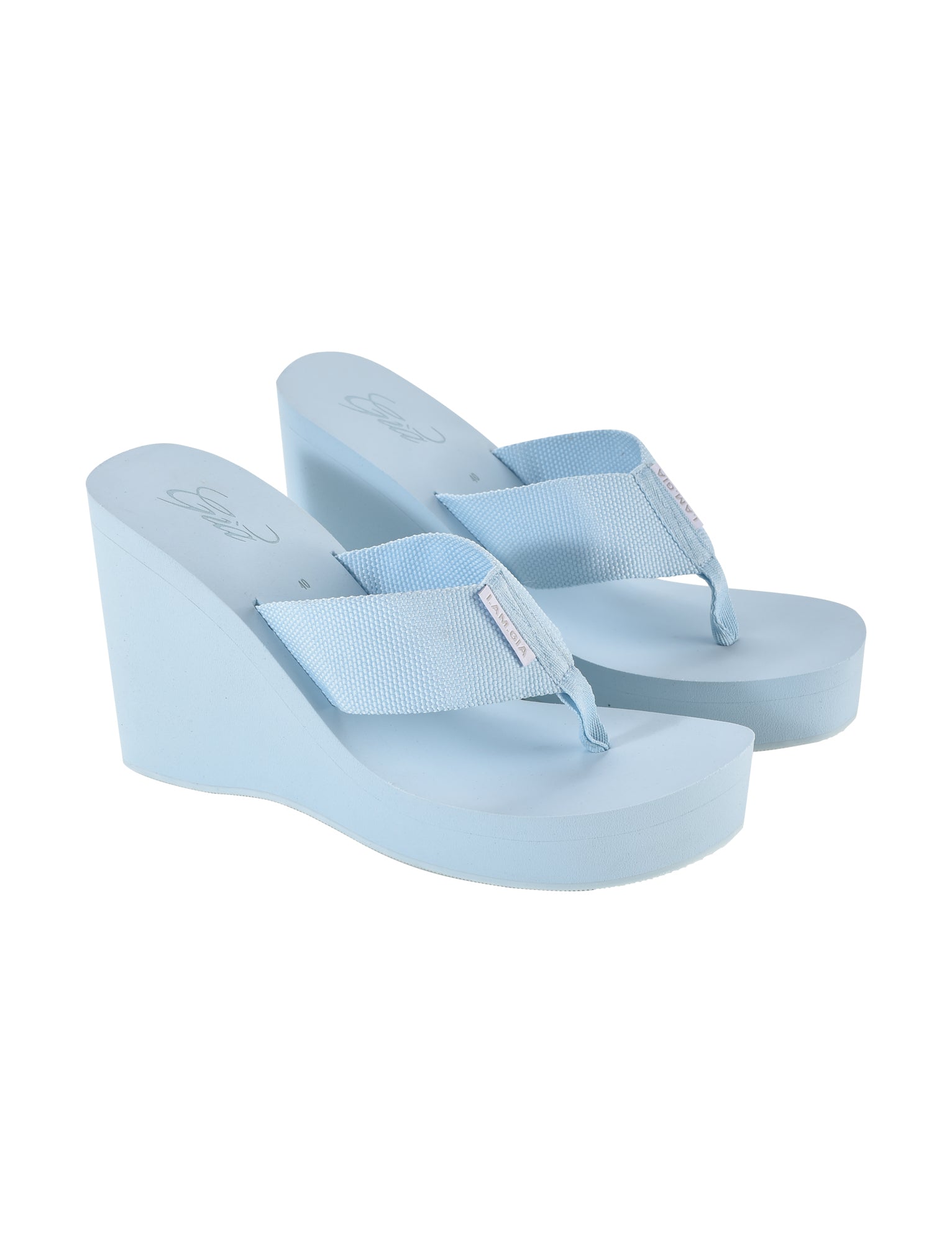 A pair of I.AM.GIA SHELBY FLIP FLOP in baby blue, featuring a textured fabric strap and a thick sole. These flip-flops boast a toe-thong design and platform heel, offering both casual comfort and added height. The I.AM.GIA logo is visible on the insole and strap.