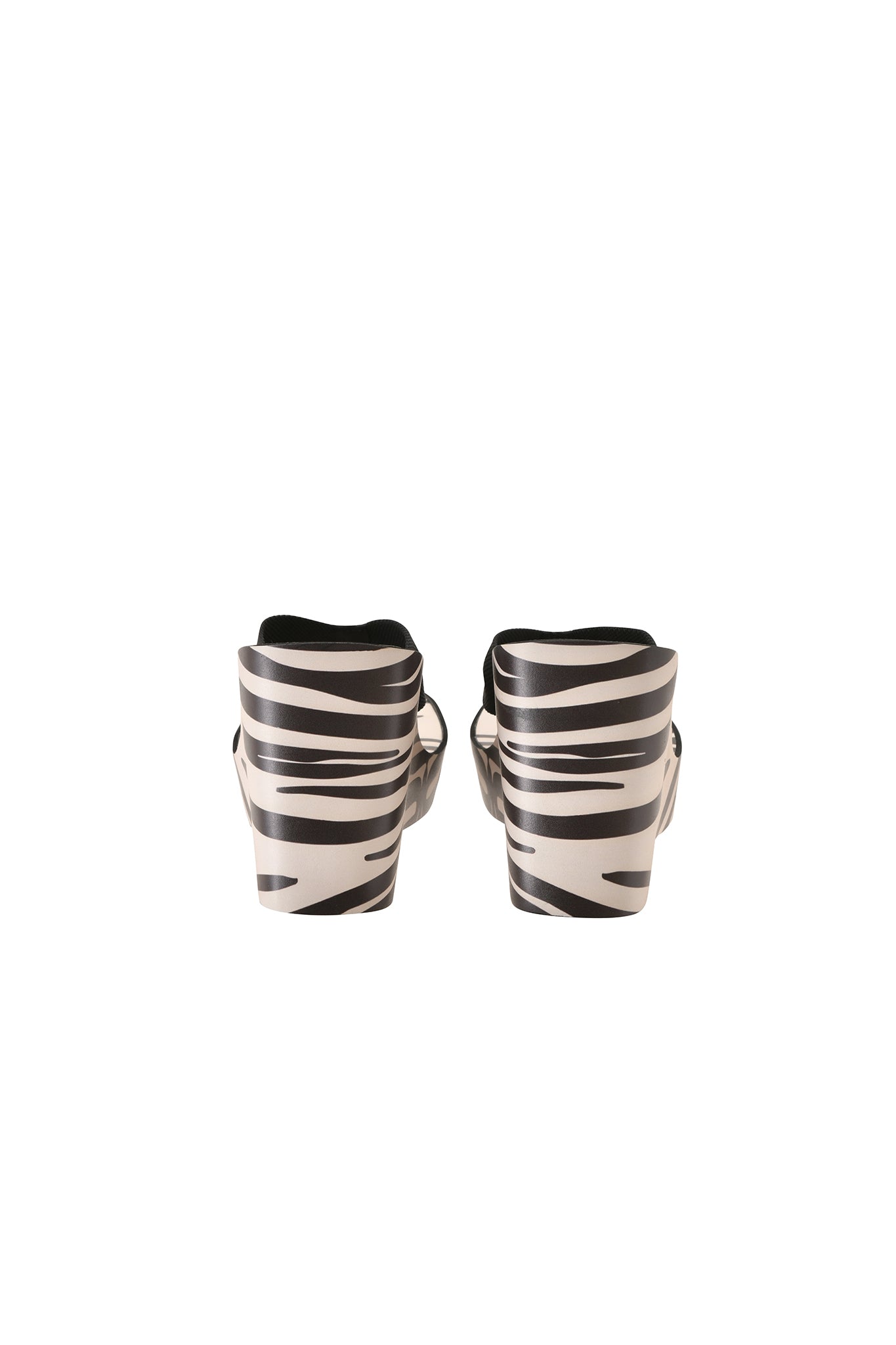 Step out in the SHELBY FLIP FLOP - FINE LINE ZEBRA by I.AM.GIA, featuring striking black and white zebra stripes and a chic platform wedge, shown from the back against a white background—perfect for adding a bold statement to your summer style.