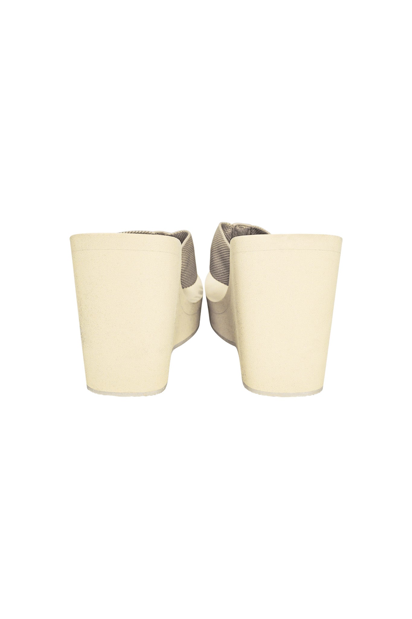A close-up view of the back of a pair of SHELBY FLIP FLOP - NEUTRAL : TAN platform shoes by I.AM.GIA. The shoes feature a chunky heel, and the soft, textured fabric adds an elegant touch. The image is presented on a white background.