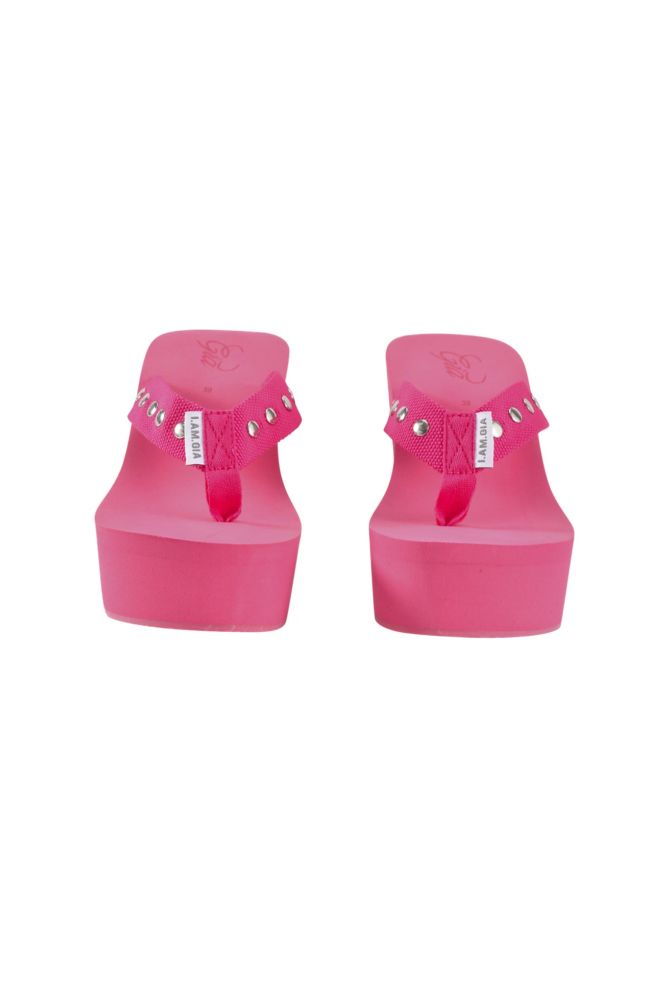 The I.AM.GIA SHELBY STUDDED FLIP FLOP 2.0 in hot pink features studded straps and white brand tags, shown from the front against a white background.
