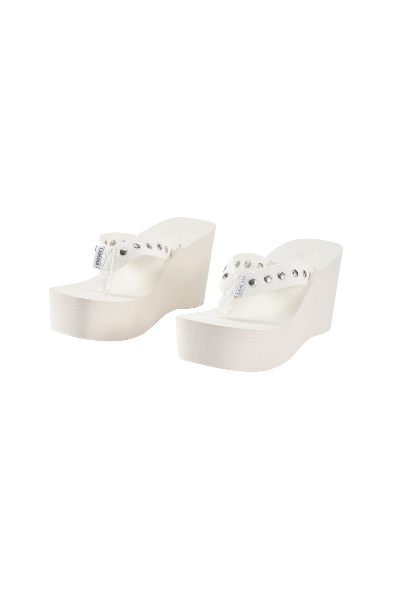The I.AM.GIA SHELBY STUDDED FLIP FLOP 2.0 in white, featuring clear plastic straps and silver stud details, is displayed on a white background.