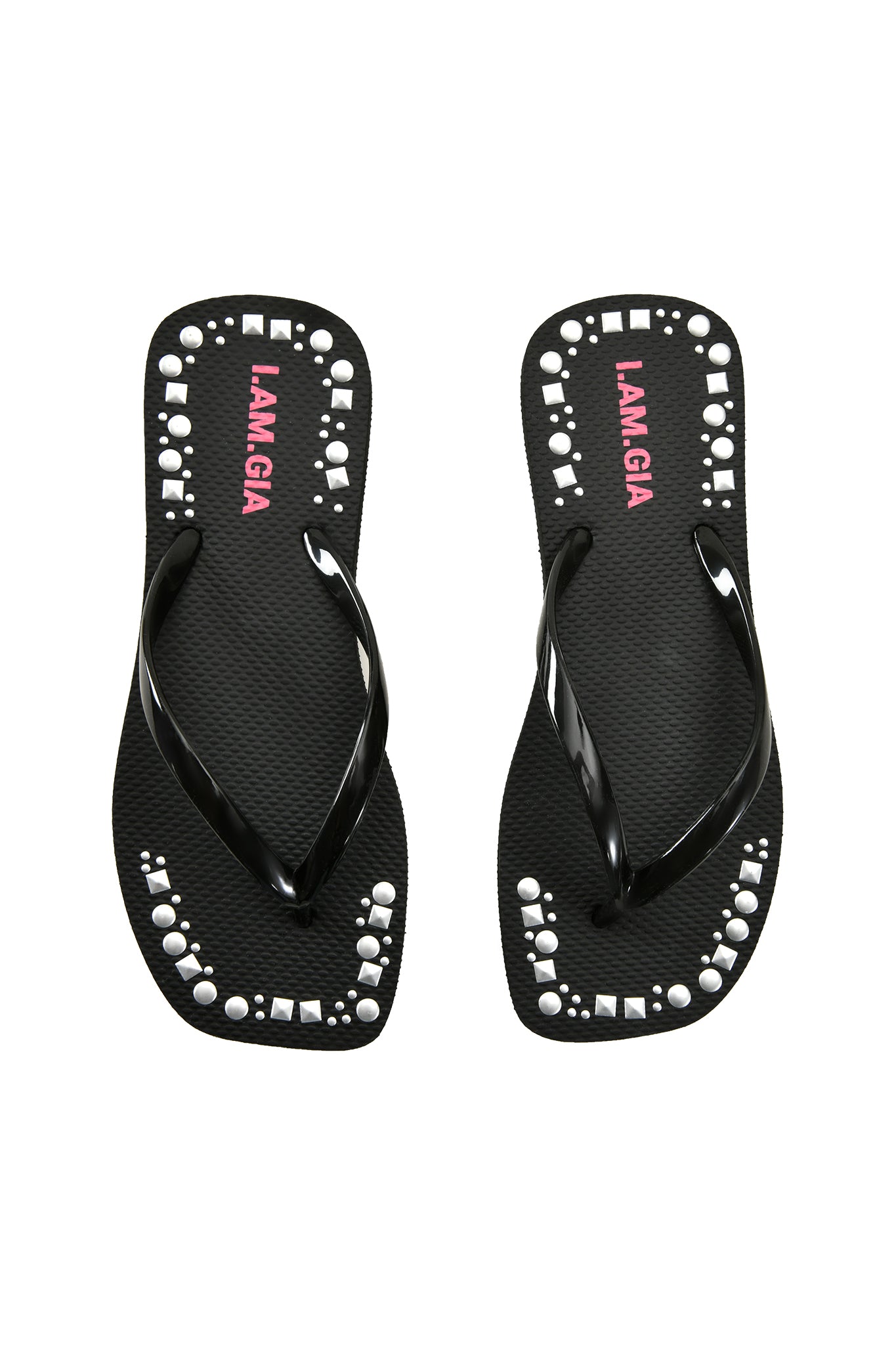 The INKA STUDDED FLIP FLOP - BLACK by I.AM.GIA features shiny black straps, extra-soft foam footbeds with pink "I.AM.GIA" text, and white geometric studs along the edges.