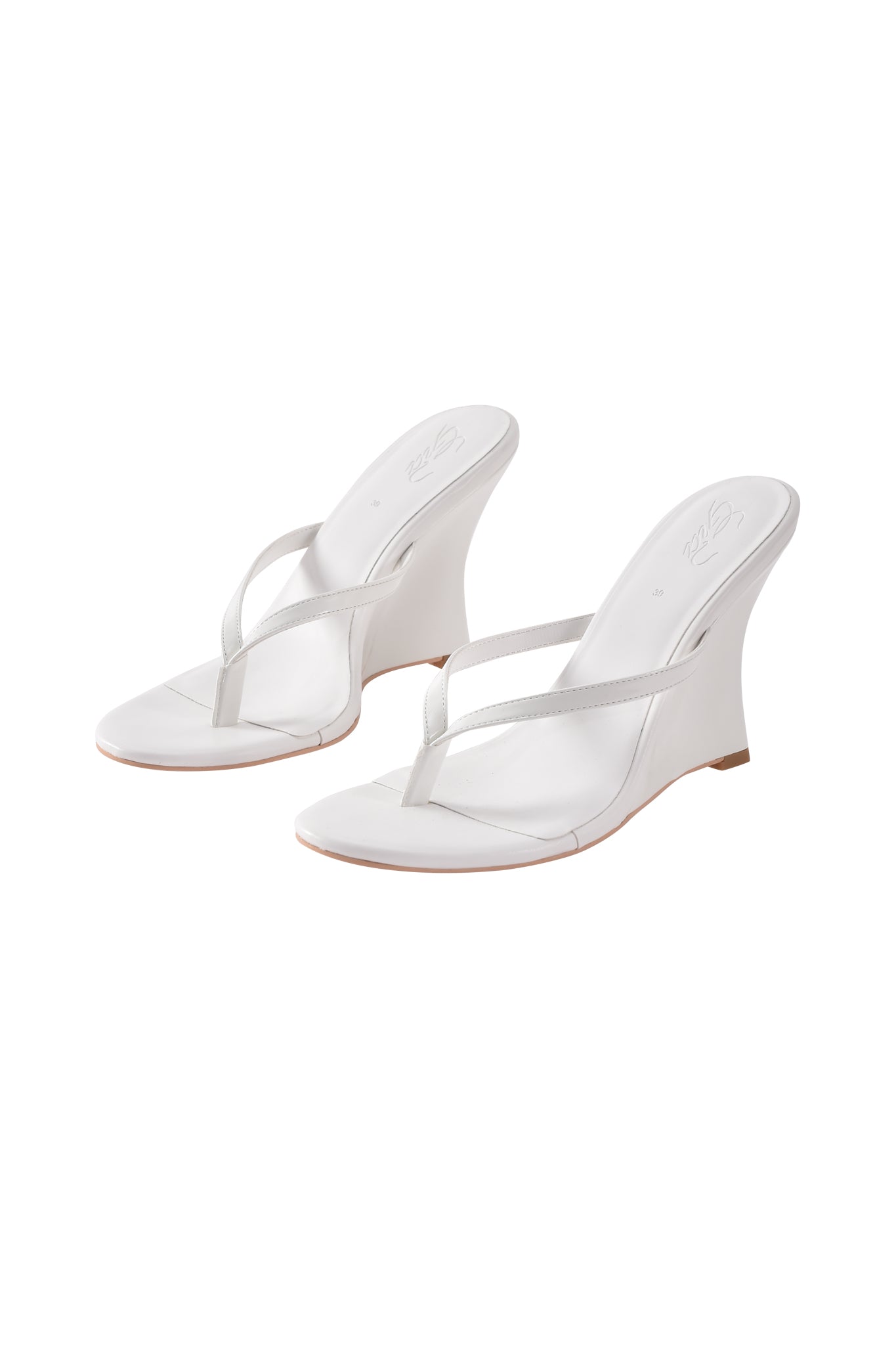The VIKTORIA WEDGE HEEL in white by I.AM.GIA features thin faux leather straps, open toes, slightly curved wedge heels, and a minimalist modern design.