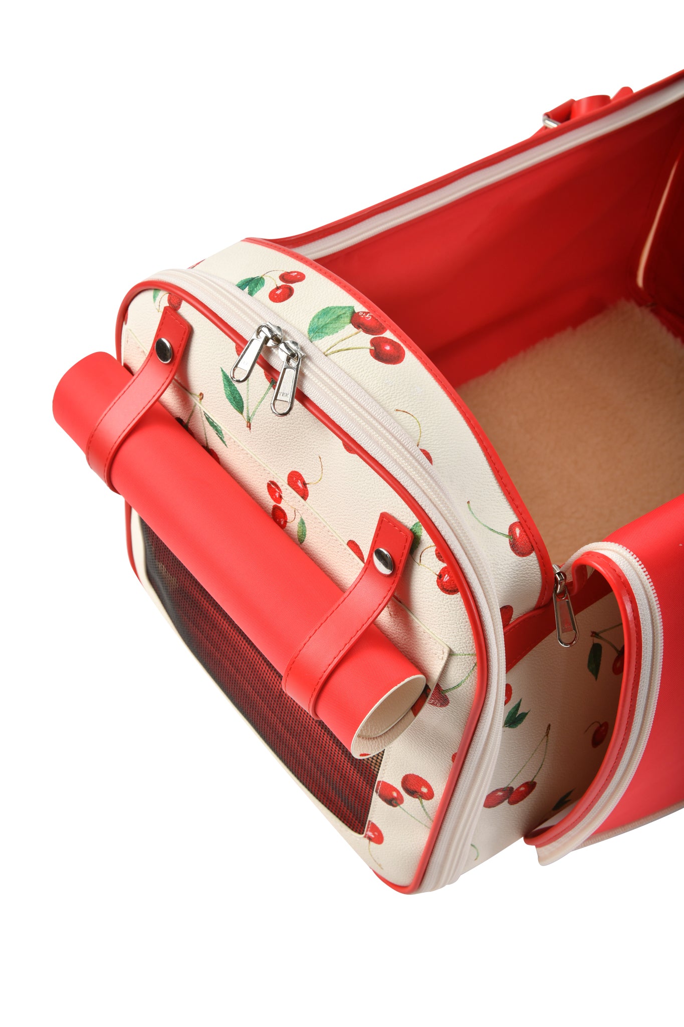 A close-up of the I.AM.GIA TRIXX PET CARRIER - CHERRY ON TOP shows red accents, mesh ventilation, and a soft beige lining. The small pet carrier is partially unzipped, revealing its cozy interior.