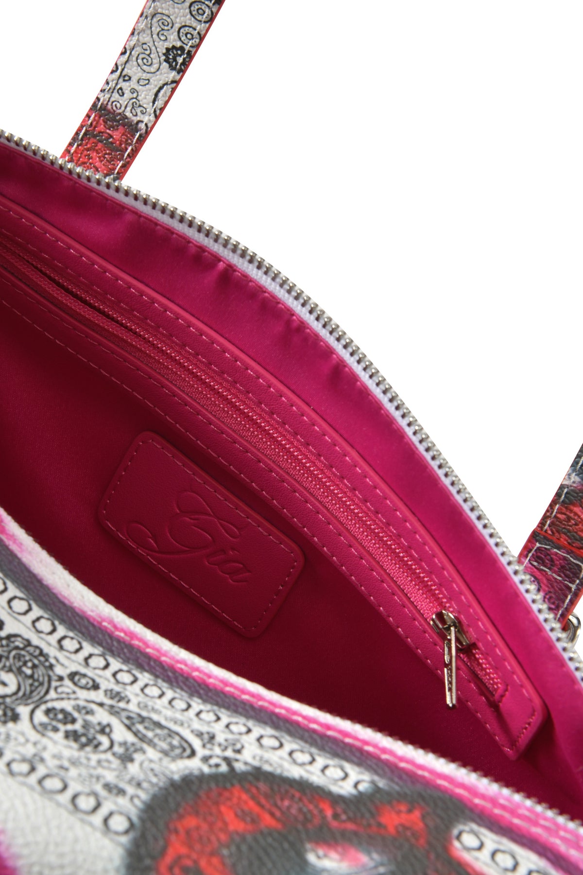 Close-up of the T-REX BARREL BAG - PAISLEY FACE by I.AM.GIA, featuring a pink faux leather interior, inner zip pocket, stitched “Gia” label, patterned exterior fabric, and visible shoulder strap.