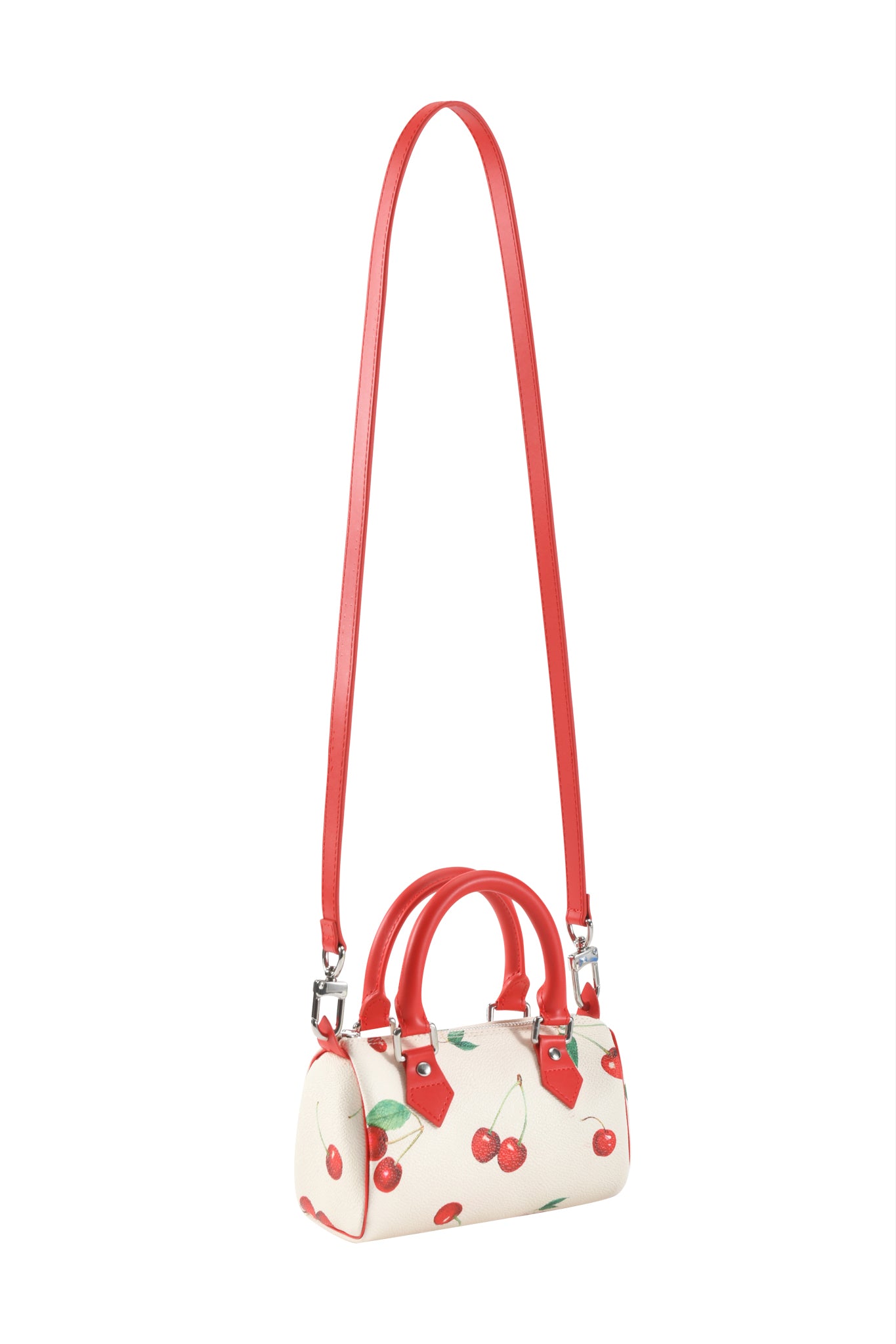 The NIKA MINI BAG - CHERRY ON TOP by I.AM.GIA is a small white barrel purse with a playful cylindrical shape, red handles, long red shoulder strap, silver hardware, and signature cherry print.