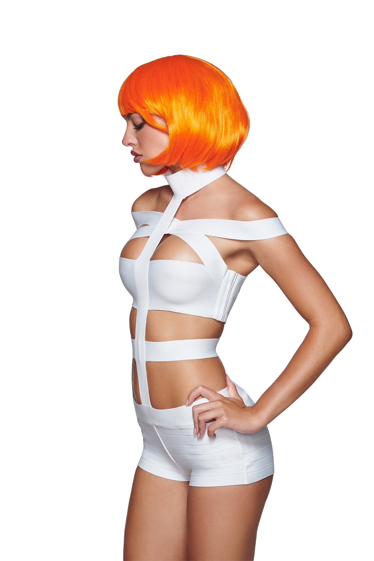 Wearing the QUINTA WIG - ORANGE by I.AM.GIA and a futuristic white strappy outfit, the model stands in profile against a plain white background, showcasing bold sci-fi costume accessories.