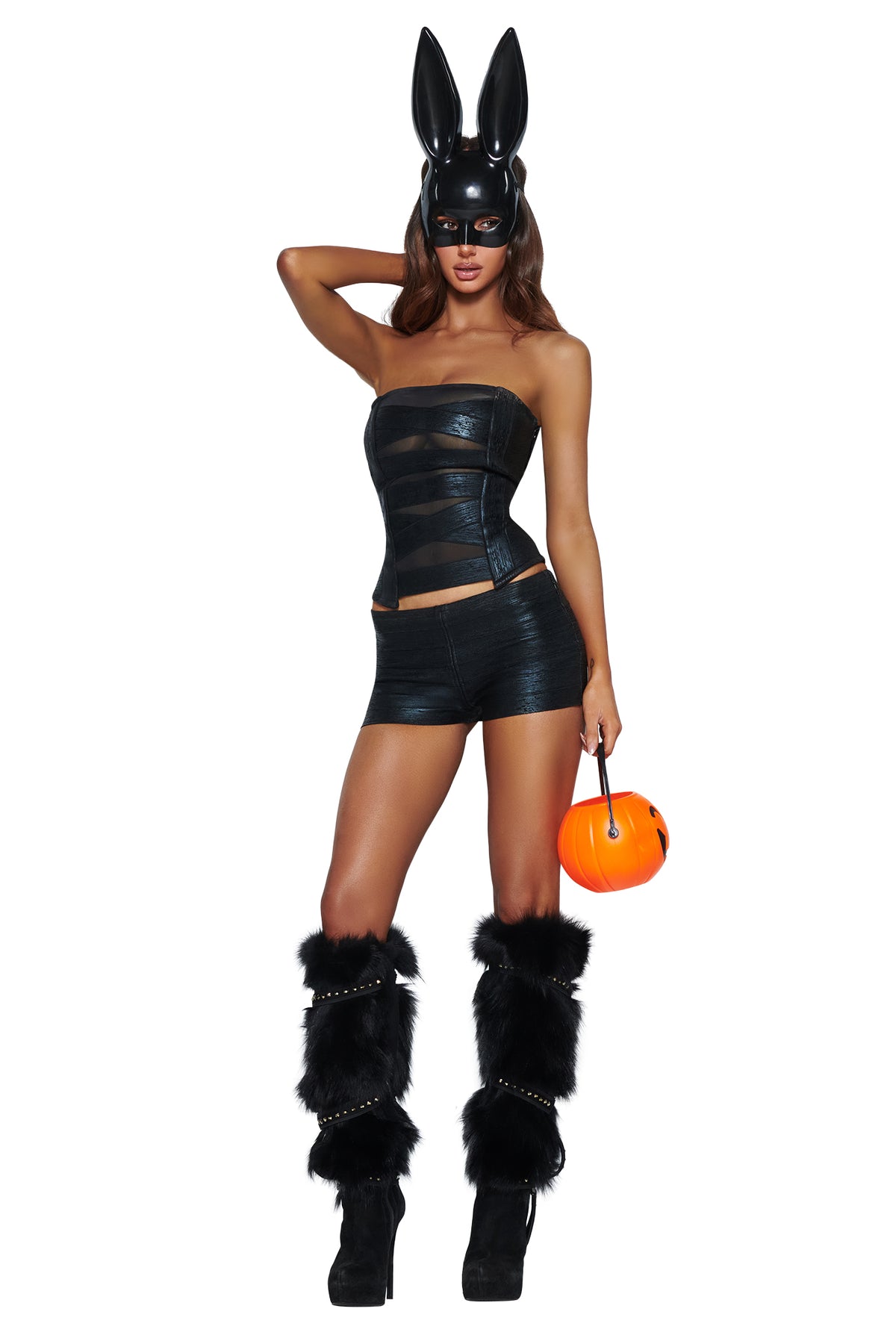 A person wearing the I.AM.GIA DOE BUNNY MASK - BLACK, paired with a strapless top, shorts, black furry leg warmers, and platform heels while holding an orange pumpkin bucket—the perfect Halloween costume accessory.