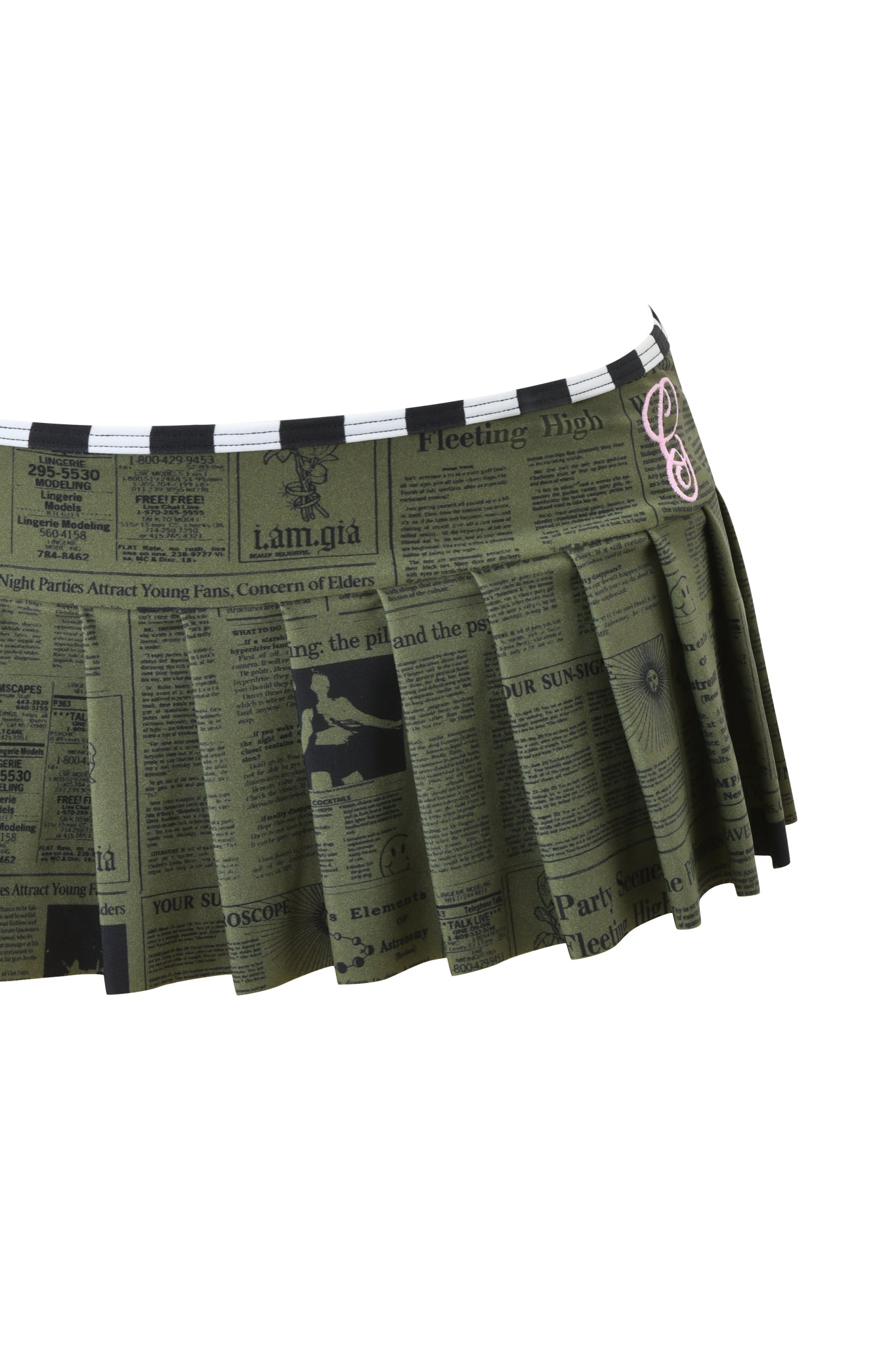 The I.AM.GIA AURETTE MICRO BIKINI SKIRT - LEFT ON READ is a green pleated micro mini skirt featuring a black newspaper print and a small pink music note patch on the waistband.