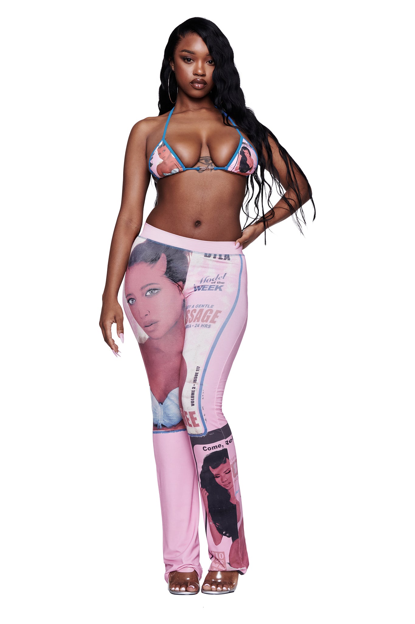 A woman wearing the I.AM.GIA T-REX AVA BIKINI TOP in pink and pink printed pants with vintage-style portraits stands with one hand on her hip against a white background.
