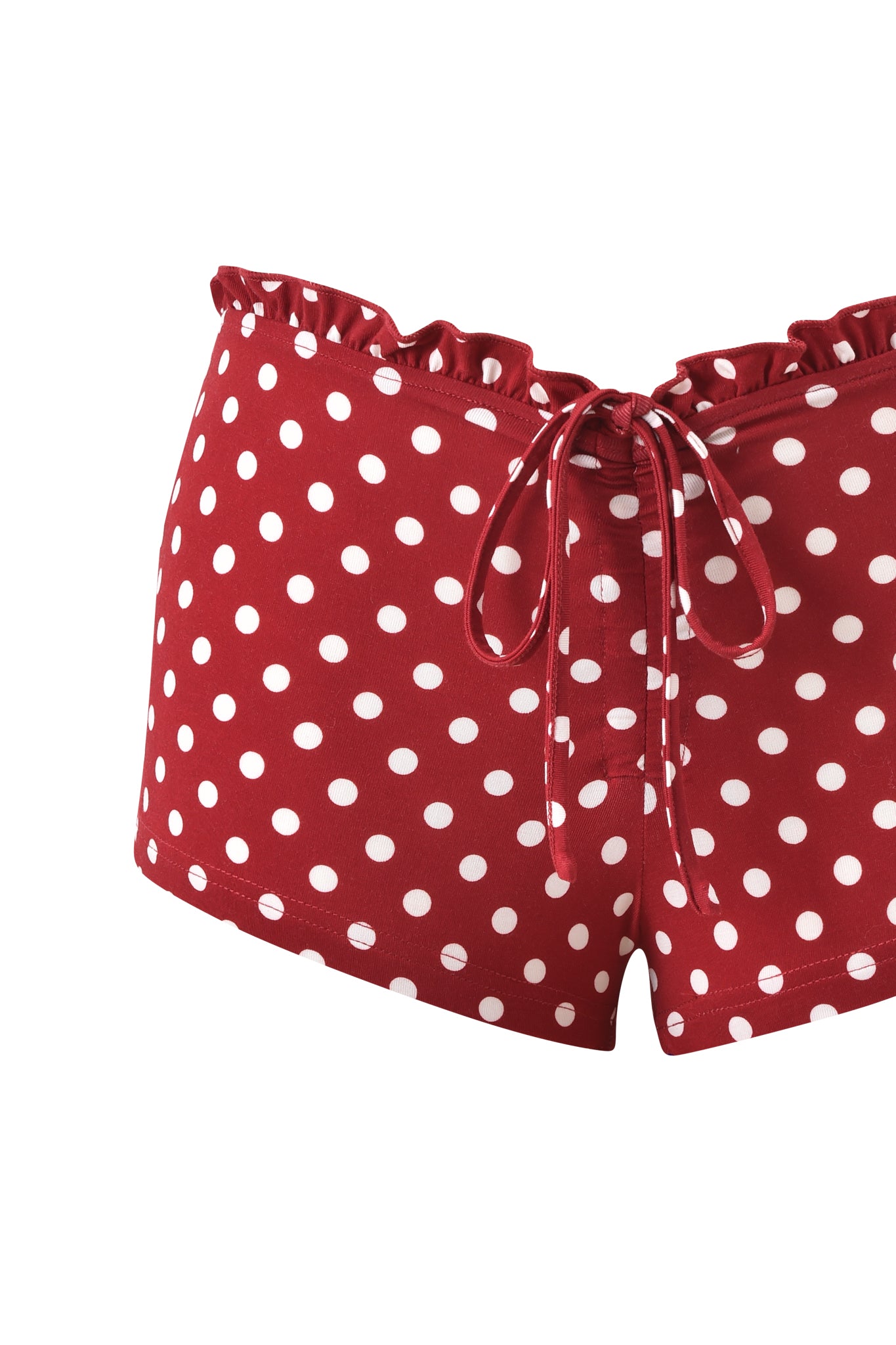 The MELANIE SHORT - RED POLKA DOT by I.AM.GIA features a ruffled waistband, front drawstring bow, and red and white polka dot print, crafted from soft bamboo jersey. Shown against a white background.