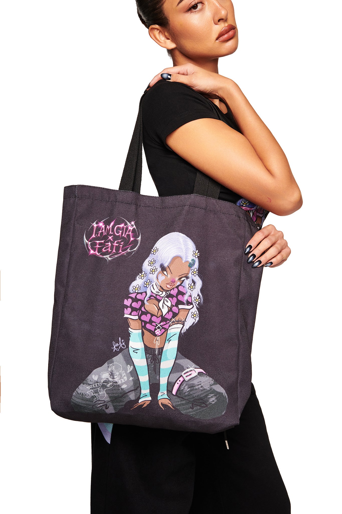 A woman holds the I.AM.GIA FAFI TOTE BAG - BLACK, featuring exclusive FAFI artwork of a character with long white hair amid pink hearts and "I'm Girl" graffiti text.